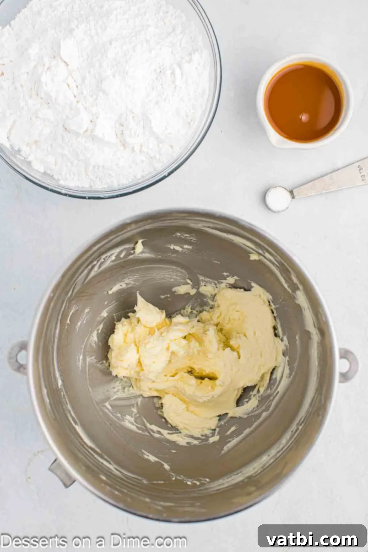 Softened butter being beaten in a bowl with a handheld mixer until light and fluffy.