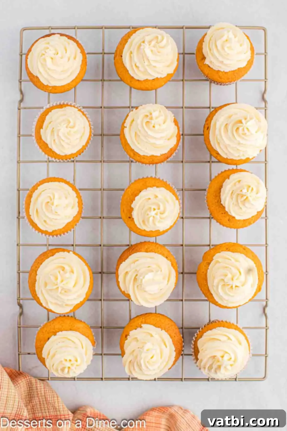 Decorated butterscotch cupcakes topped with creamy frosting and a drizzle, arranged on a wire cooling rack.