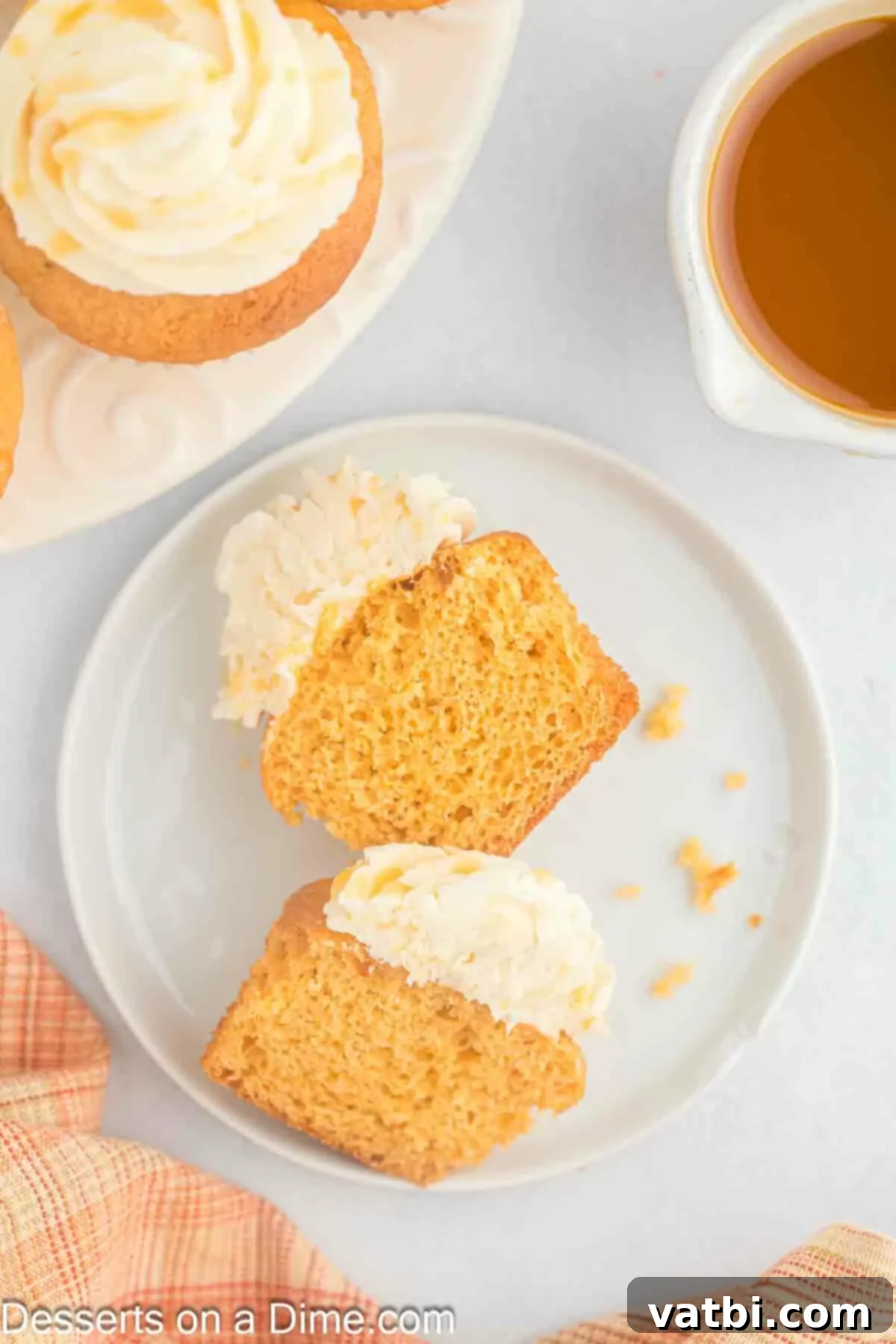 A delicious Butterscotch Cupcake cut in half, revealing the moist interior, served on a white plate.