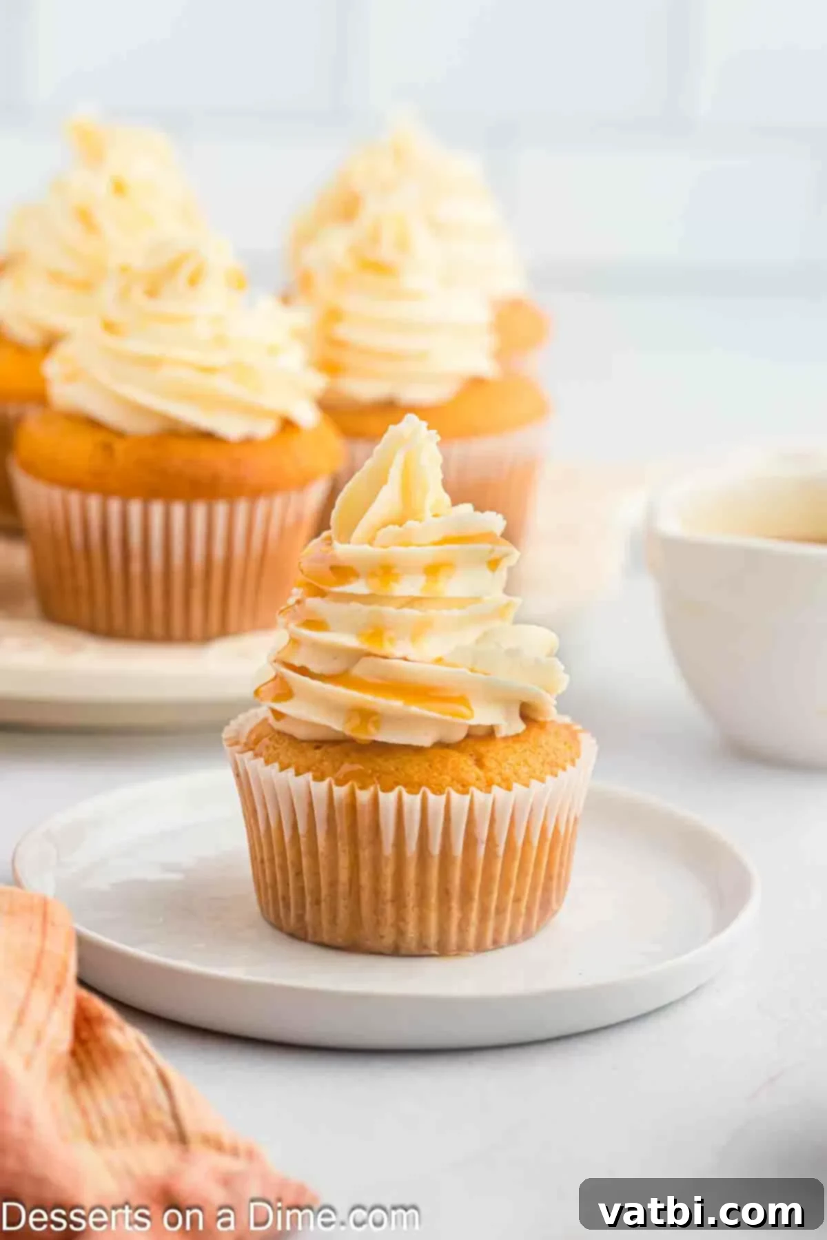 A plate of beautifully frosted Butterscotch Cupcakes, artfully drizzled with more butterscotch sauce, ready for serving.