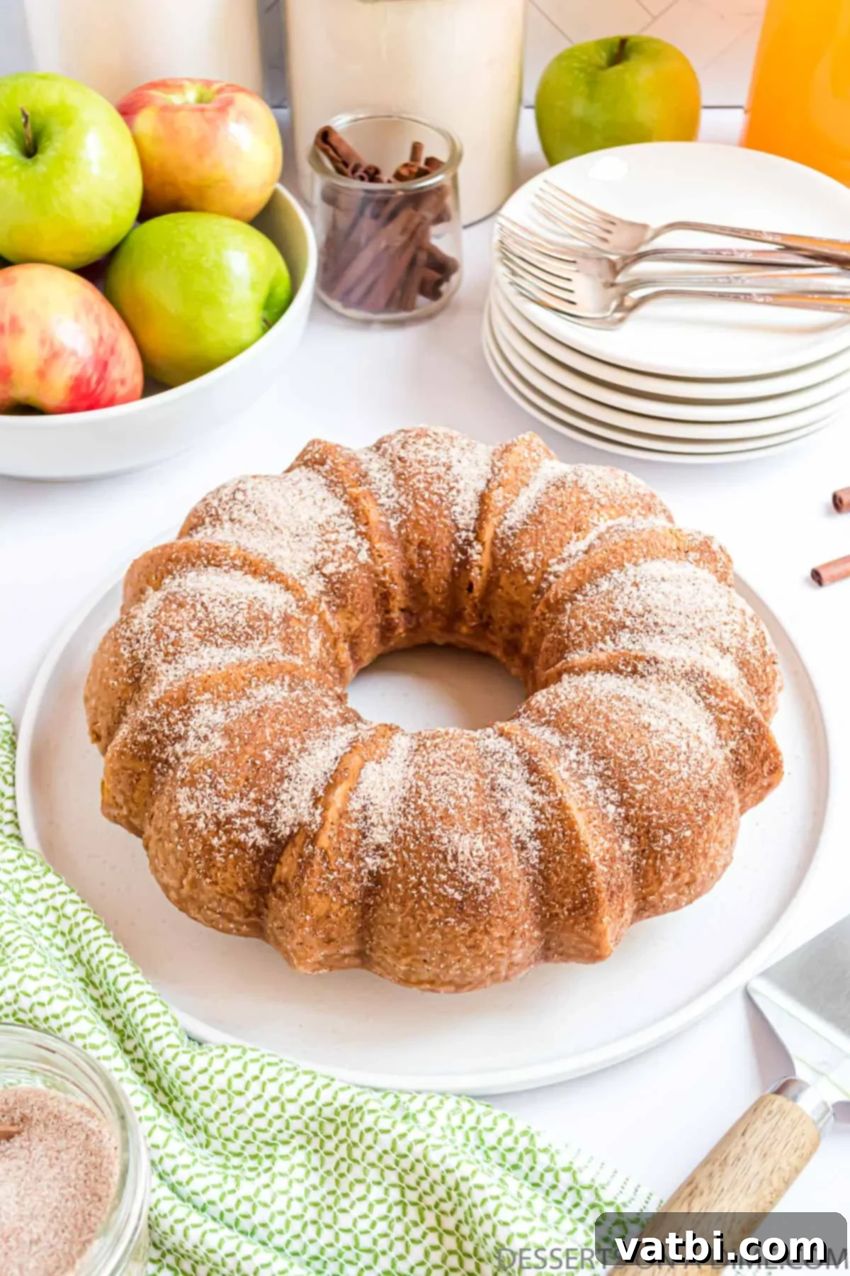 Harvest Apple Cider Bundt 12 A perfectly baked and coated Apple Cider Bundt Cake displayed on a white plate, ready to be sliced and enjoyed as a dessert.