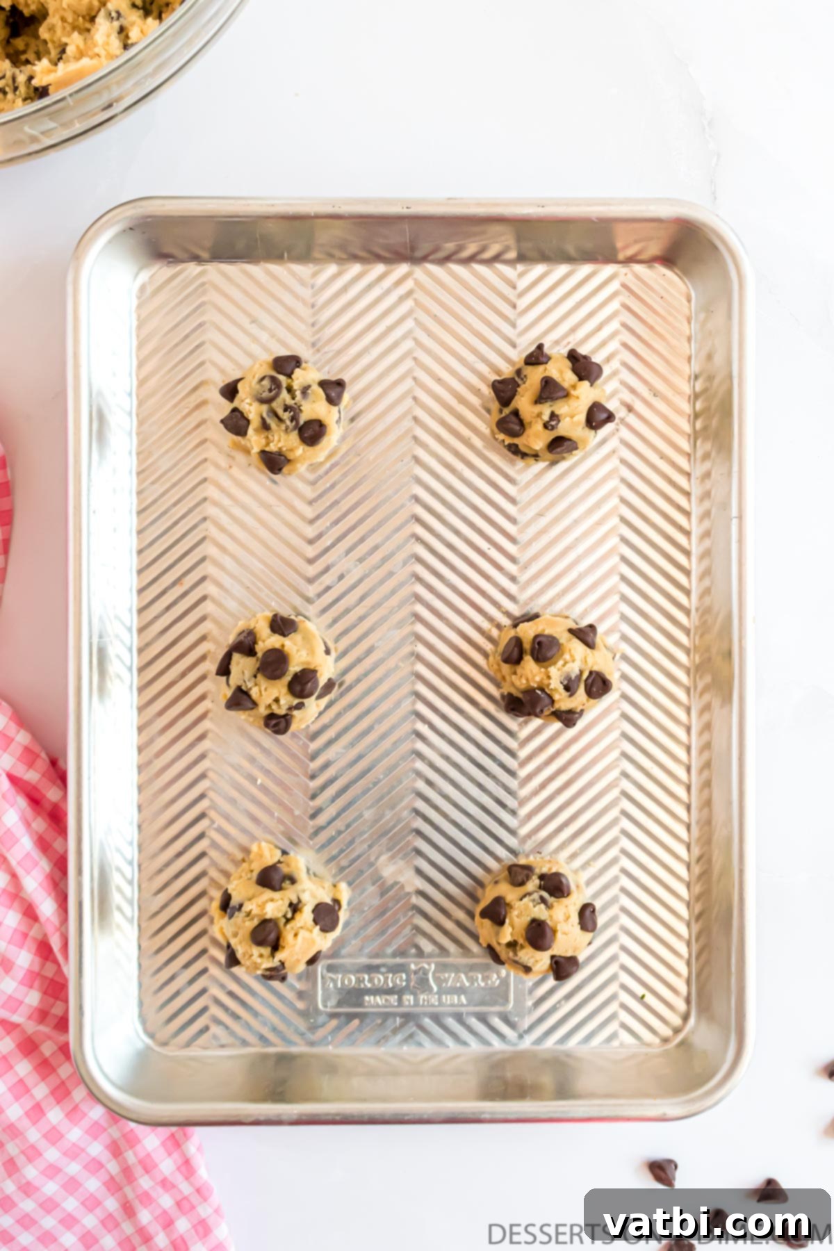 Decadent Cream Cheese Chocolate Chip Cookies 9 Portions of cream cheese chocolate chip cookie dough arranged on a parchment-lined baking sheet.
