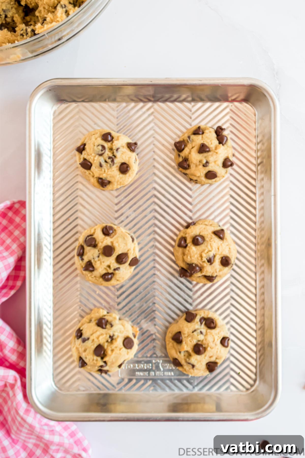 Decadent Cream Cheese Chocolate Chip Cookies 10 Freshly baked cream cheese chocolate chip cookies cooling on a parchment-lined baking sheet after coming out of the oven.