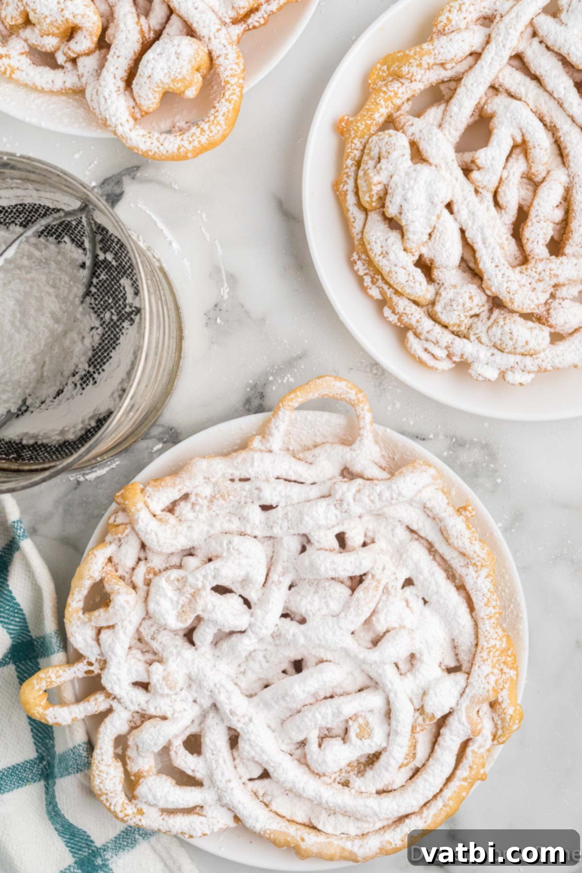 Sweet Funnel Cake Perfection 2 A golden-brown funnel cake, generously topped with powdered sugar, rests on a plate, ready to be enjoyed.