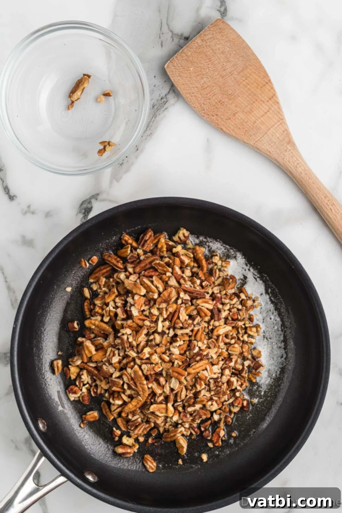 Classic Butter Pecan Cookies 4 Chopped pecans being gently stirred in a skillet with melted butter, beginning the toasting process for enhanced flavor.
