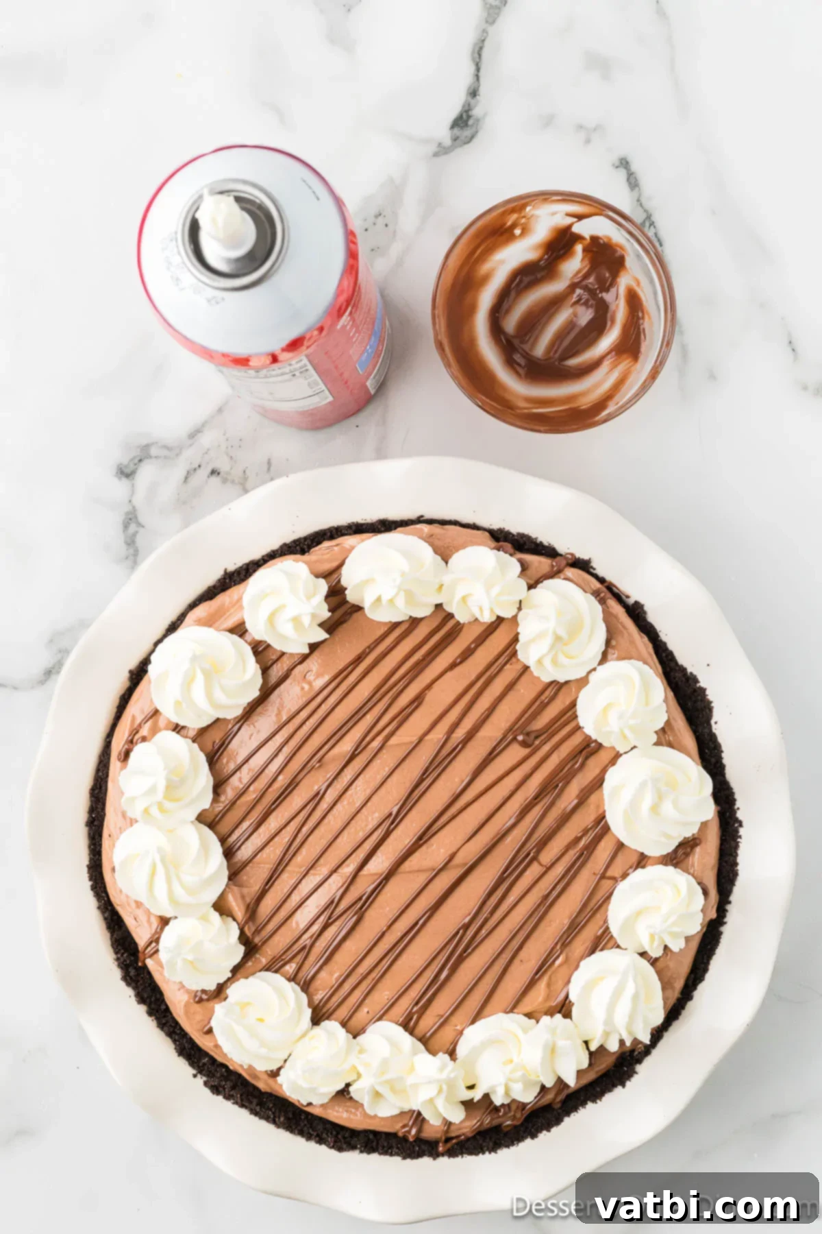 Decadent No Bake Nutella Cheesecake 11 Pie garnished with melted nutella and whipped cream.