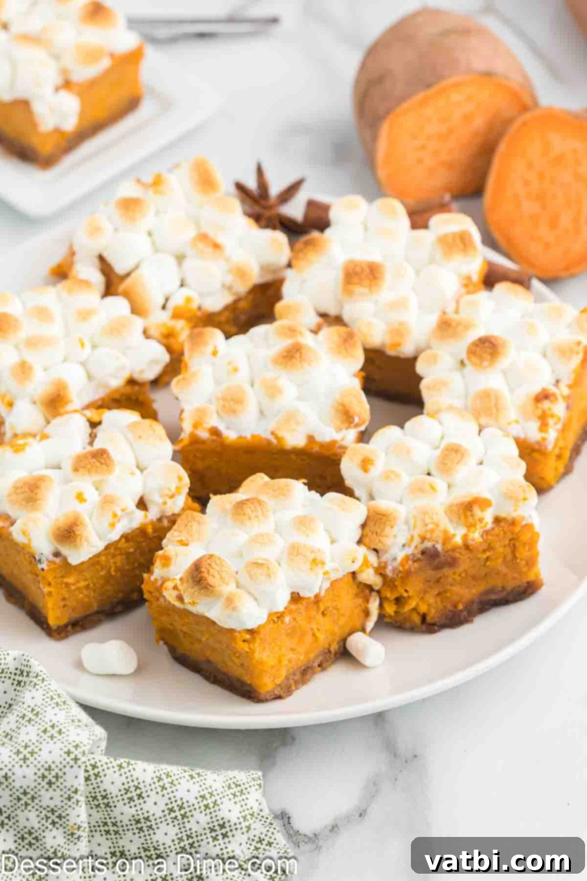 Sweet potato pie bars stacked on a plate, showcasing the graham cracker crust, creamy filling, and toasted marshmallow topping