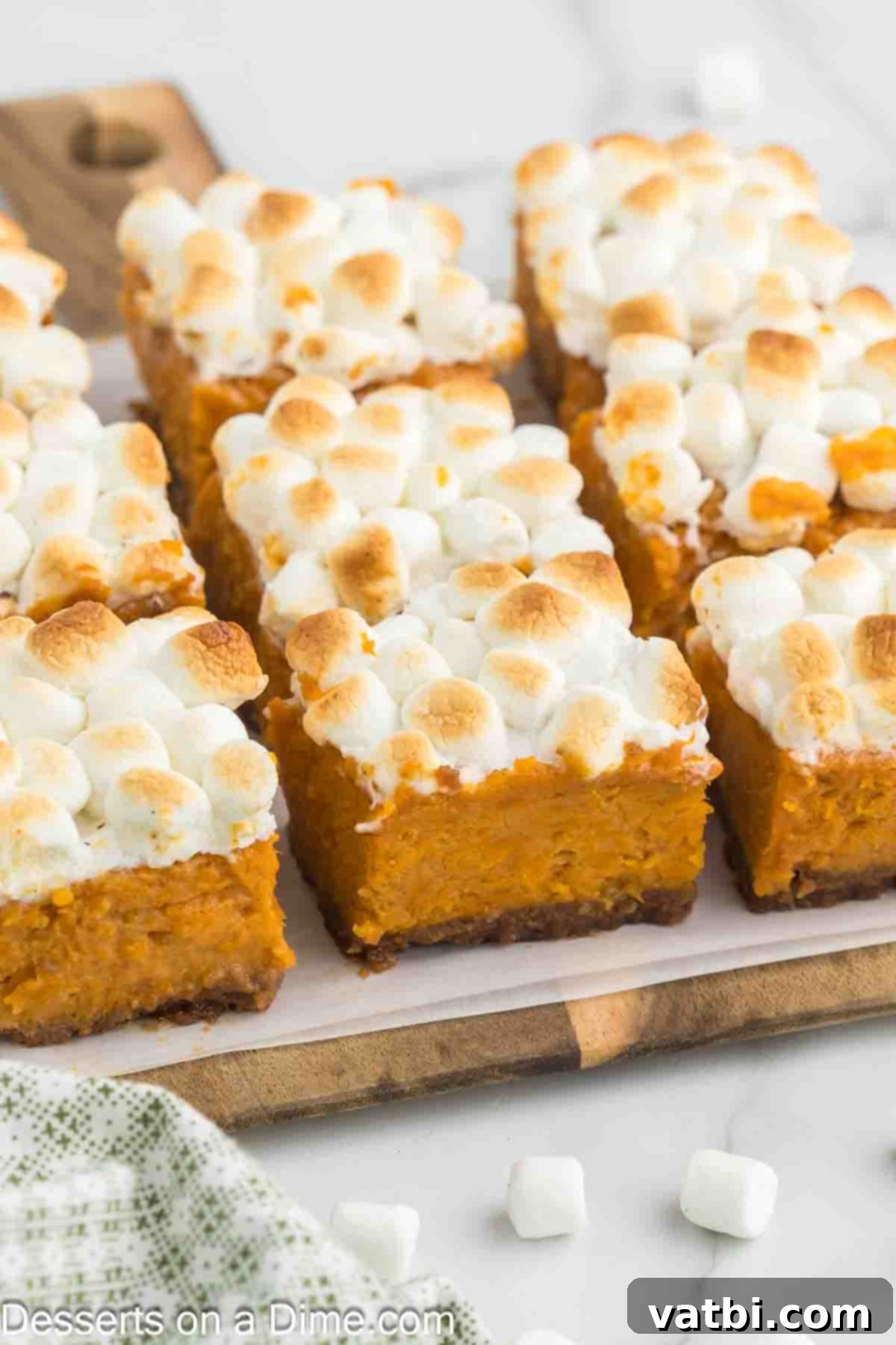 Multiple sweet potato pie bars, stacked on a plate, showcasing their inviting golden color and fluffy topping.