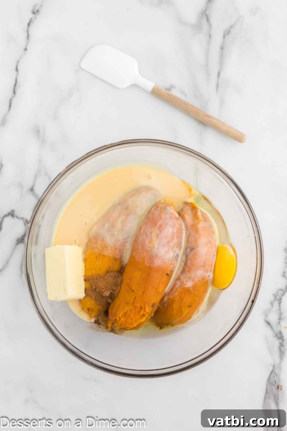 Mixing bowl with mashed sweet potatoes and sweetened condensed milk, forming the creamy filling.