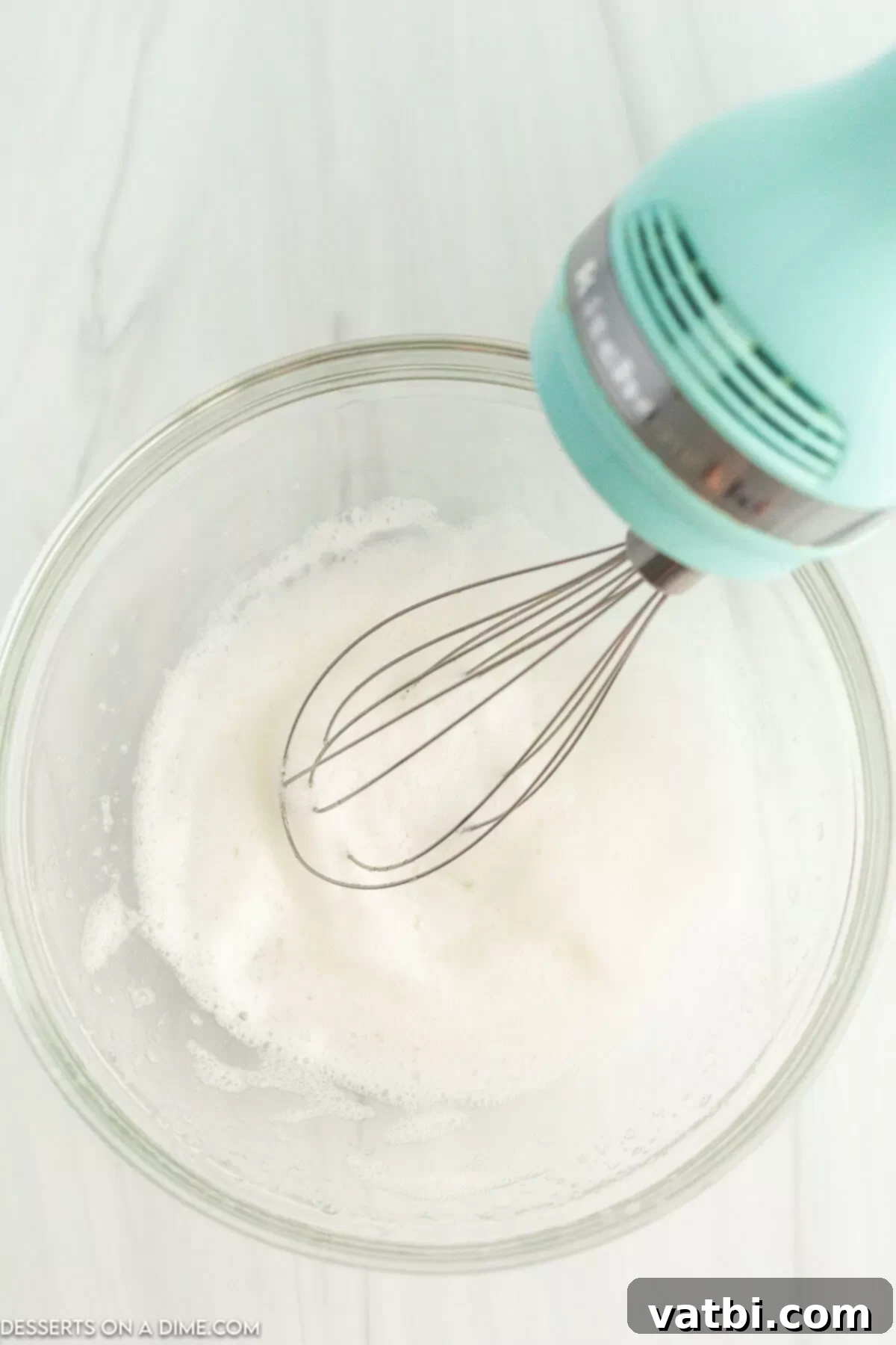 Egg whites being whipped until frothy in a bowl.