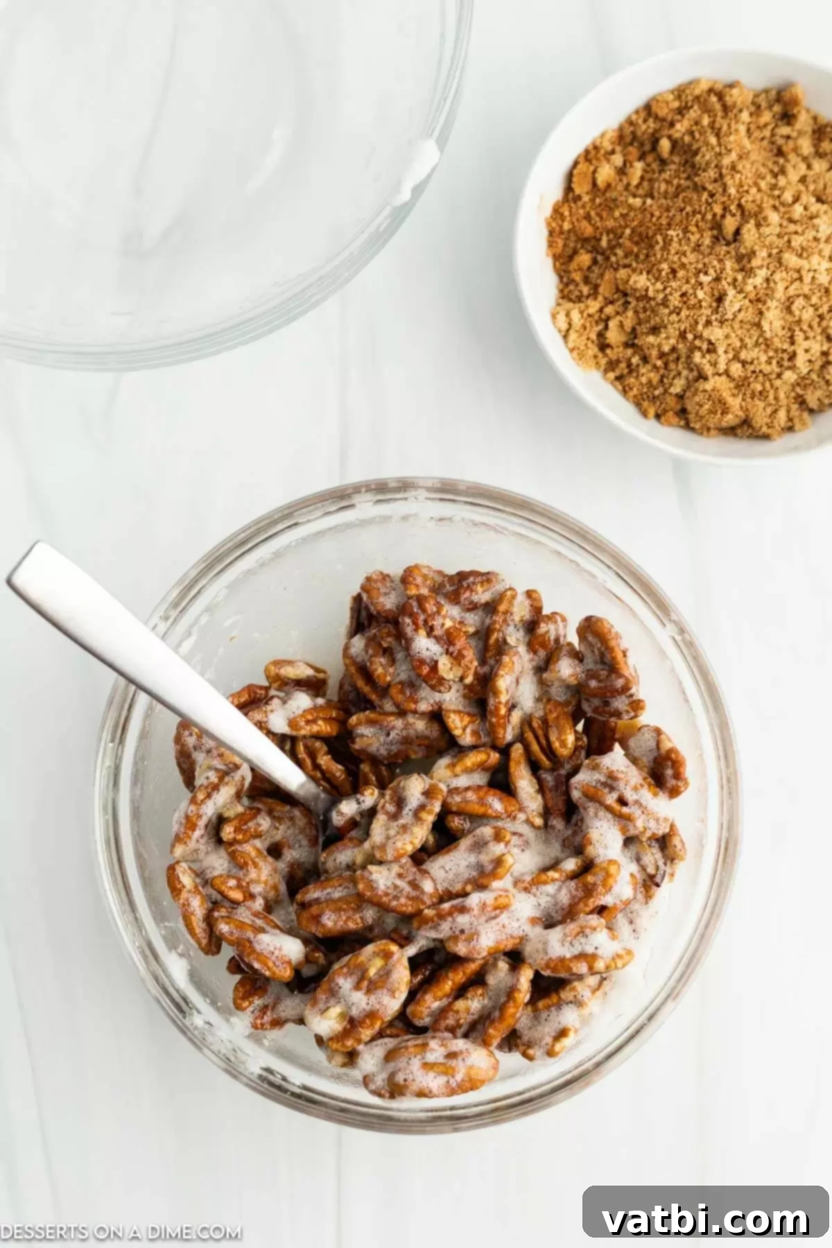 Pecan halves thoroughly coated in the frothy egg white mixture in a bowl.