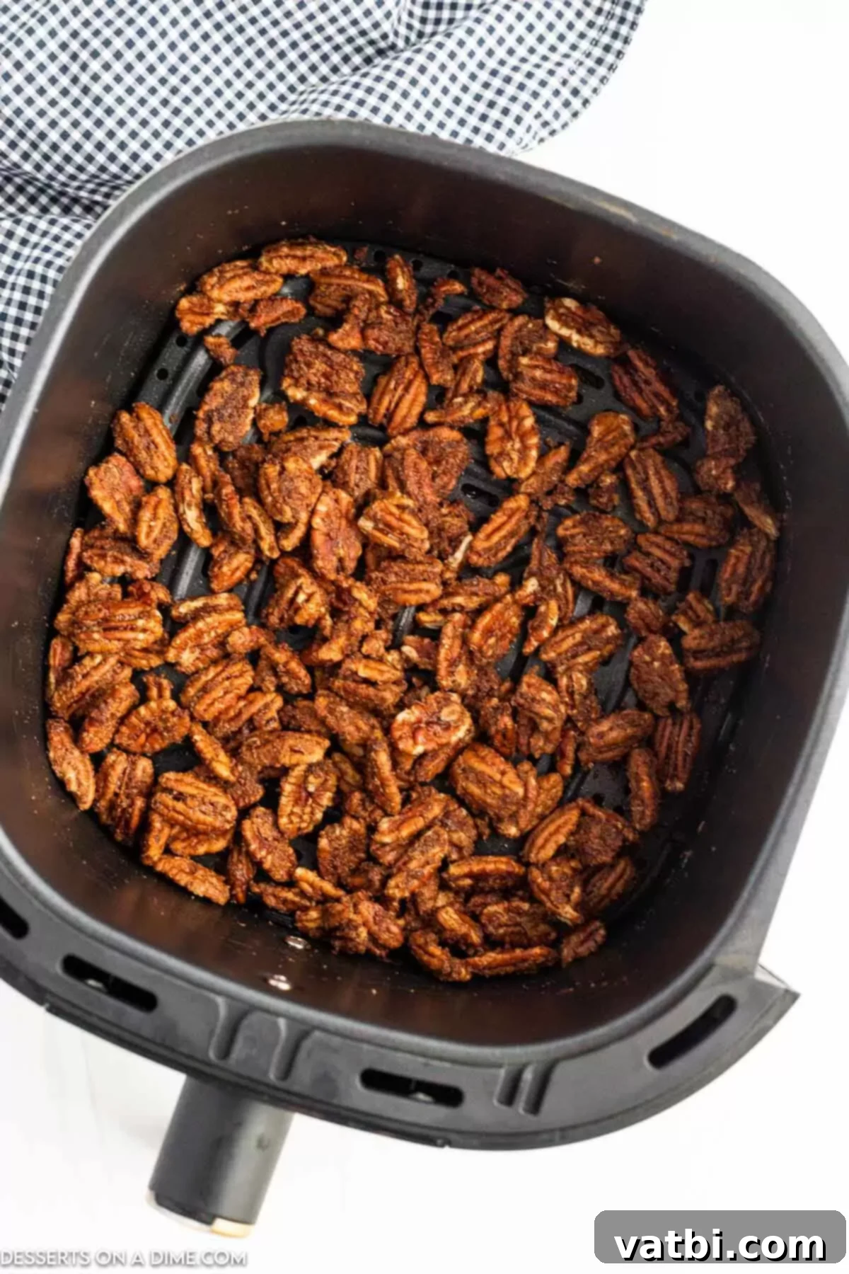 Coated pecan halves spread in a single layer in the air fryer basket, ready for cooking.