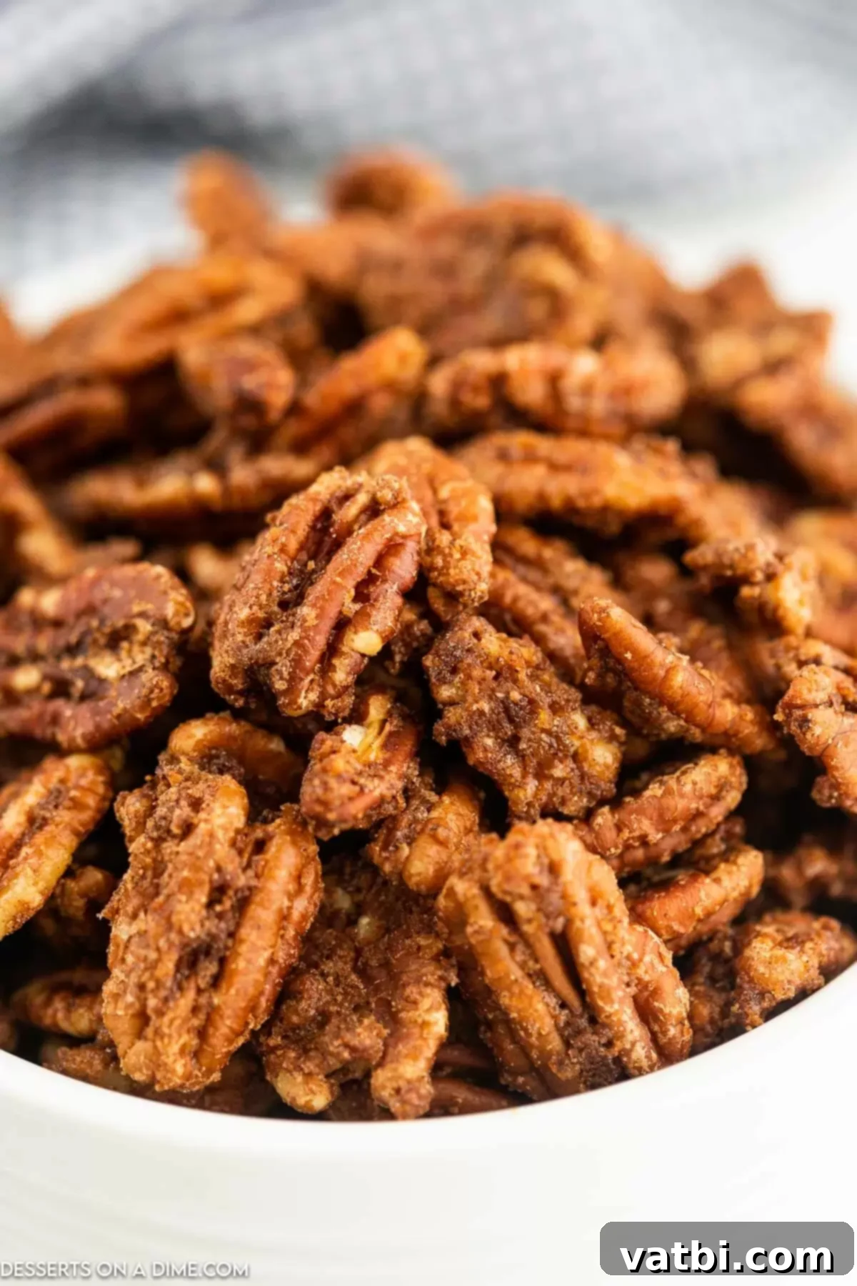 A close-up shot of crispy, golden-brown air fryer candied pecans in a rustic bowl.