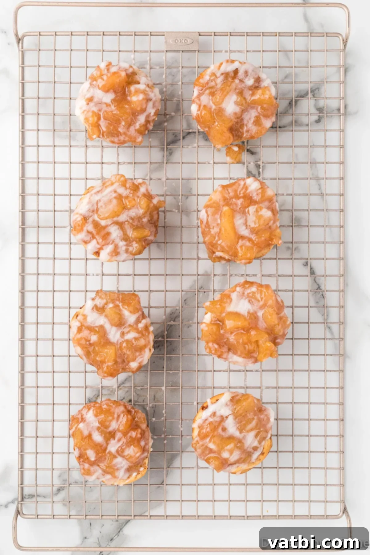 Cinnamon Roll Apple Pie Cups 9 Apple pie cups topped with glaze on wire rack.