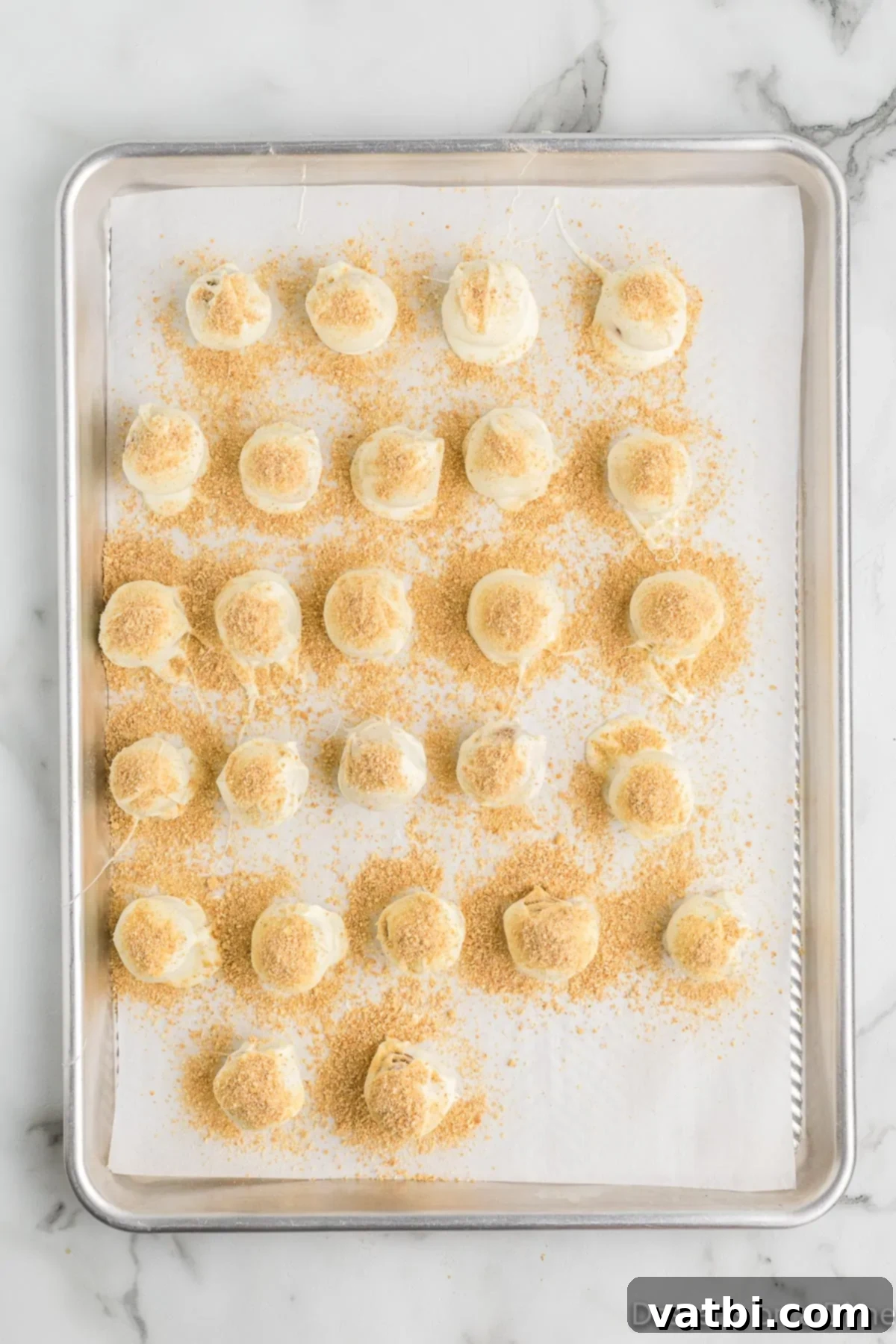 Pumpkin Spice Truffles 11 Chocolate-coated pumpkin truffles on a baking sheet, topped with graham cracker crumbs.