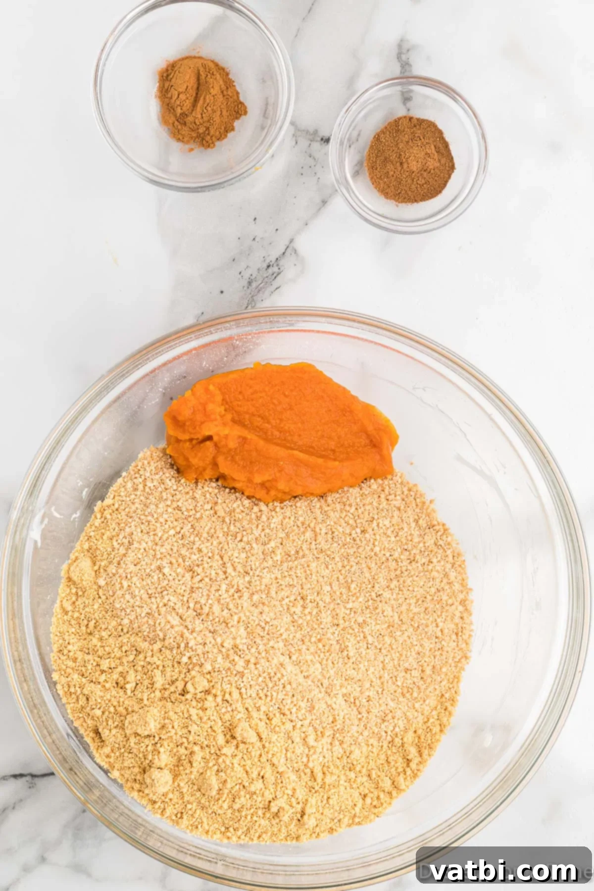 Pumpkin Spice Truffles 5 Bowl with pumpkin puree, graham cracker crumbs, pumpkin pie spice, and cinnamon, ready to be mixed.