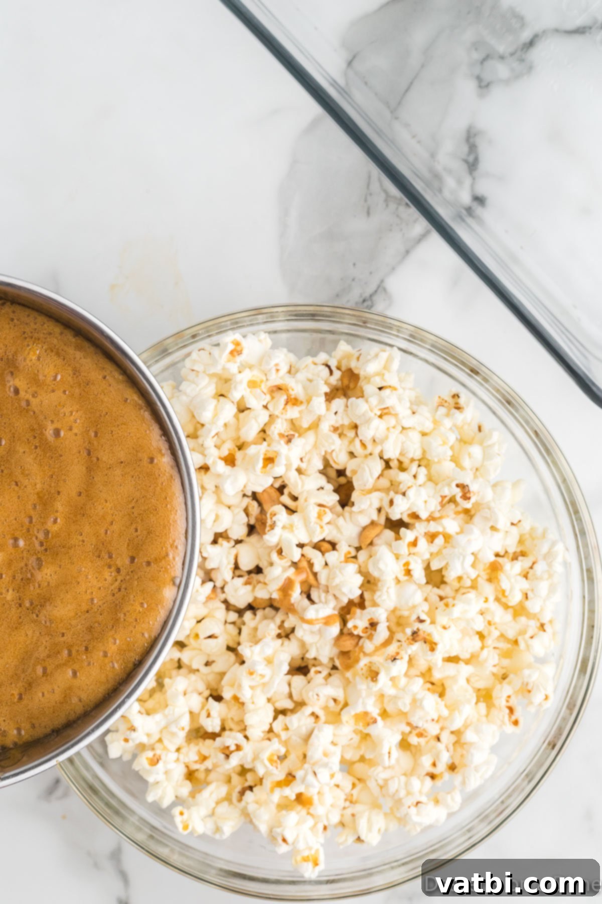 Buttery Toffee Bliss Popcorn 9 Pouring the golden toffee mixture over the popcorn in a large bowl.