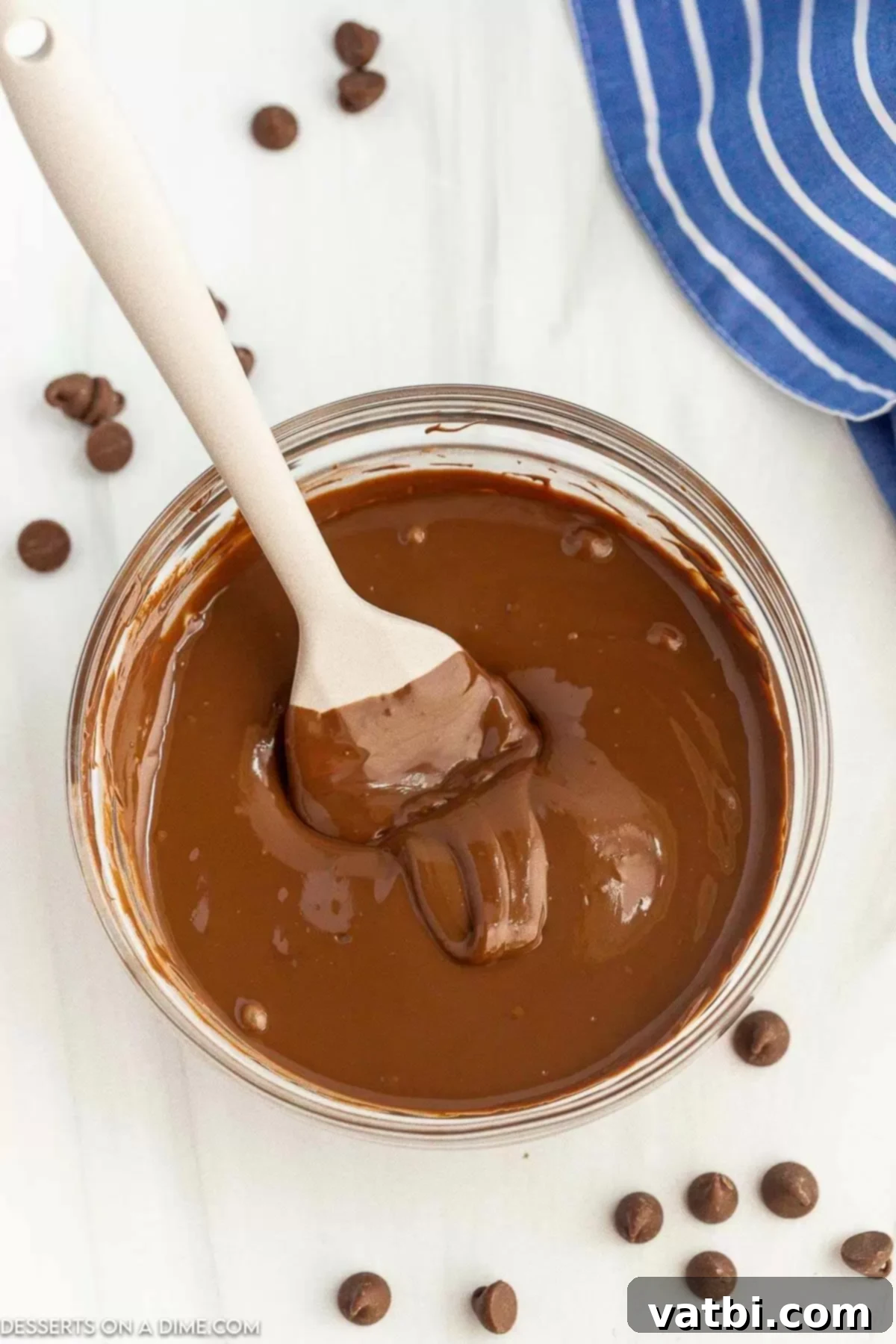 Melt Chocolate Chips Perfectly Every Time 2 Melted Chocolate in a clear bowl with a spoon, showing a smooth, glossy texture ready for use.