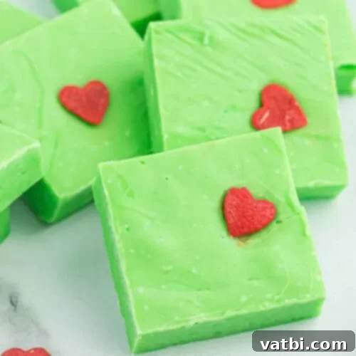 55 Festive & Easy Christmas Fudge Ideas 3 Vibrant green Grinch fudge squares topped with a small red heart sprinkle.