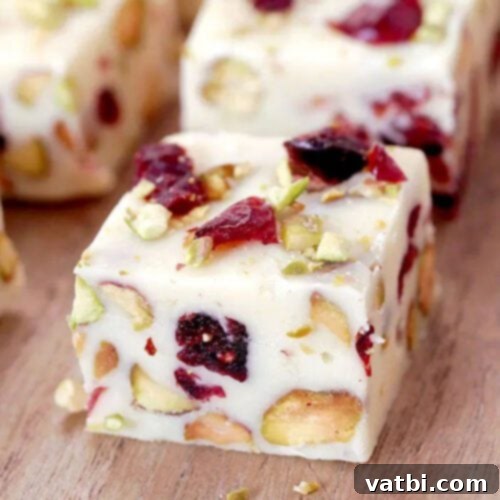55 Festive & Easy Christmas Fudge Ideas 12 Cranberry Pistachio Fudge squares with red cranberries and green pistachios.