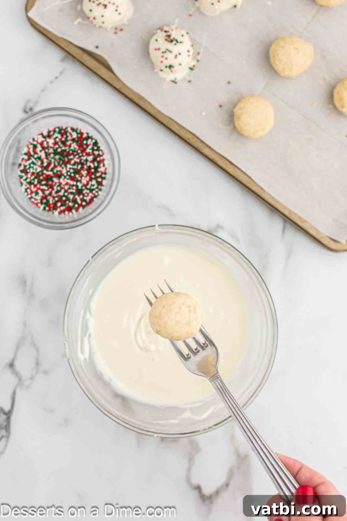 Melted chocolate in a bowl and a sugar cookie ball on a fork