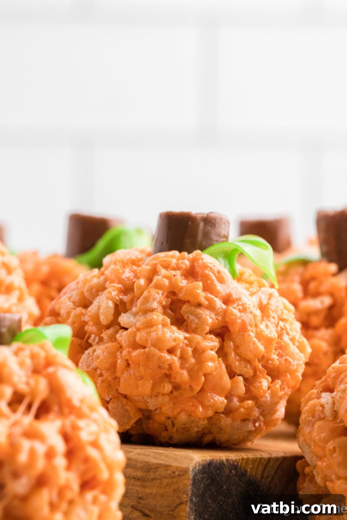 Autumn Rice Krispie Pumpkin Treats 3 Pumpkin Rice Krispy Treats on a wooden board.