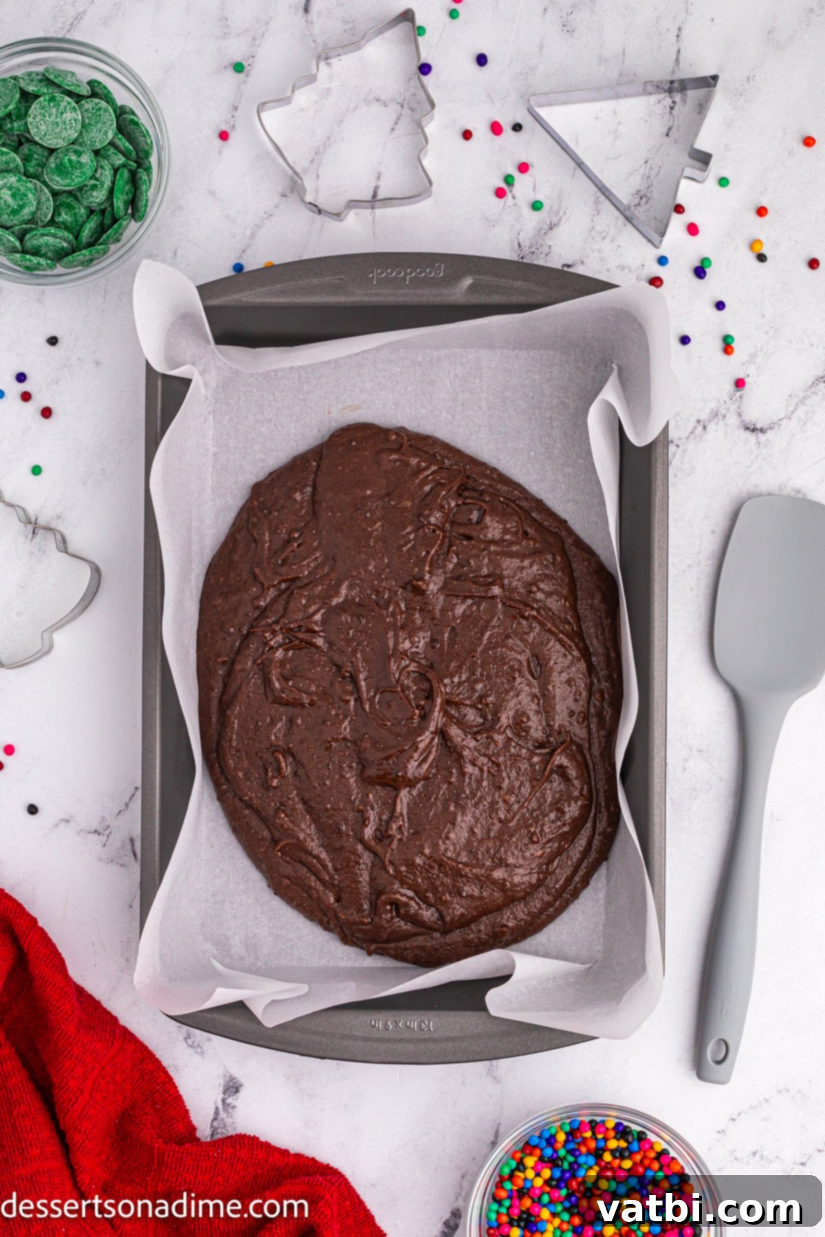 Little Debbie Inspired Christmas Tree Brownies 4 Brownie mixture being spread evenly into a parchment-lined baking pan, ready for the oven.