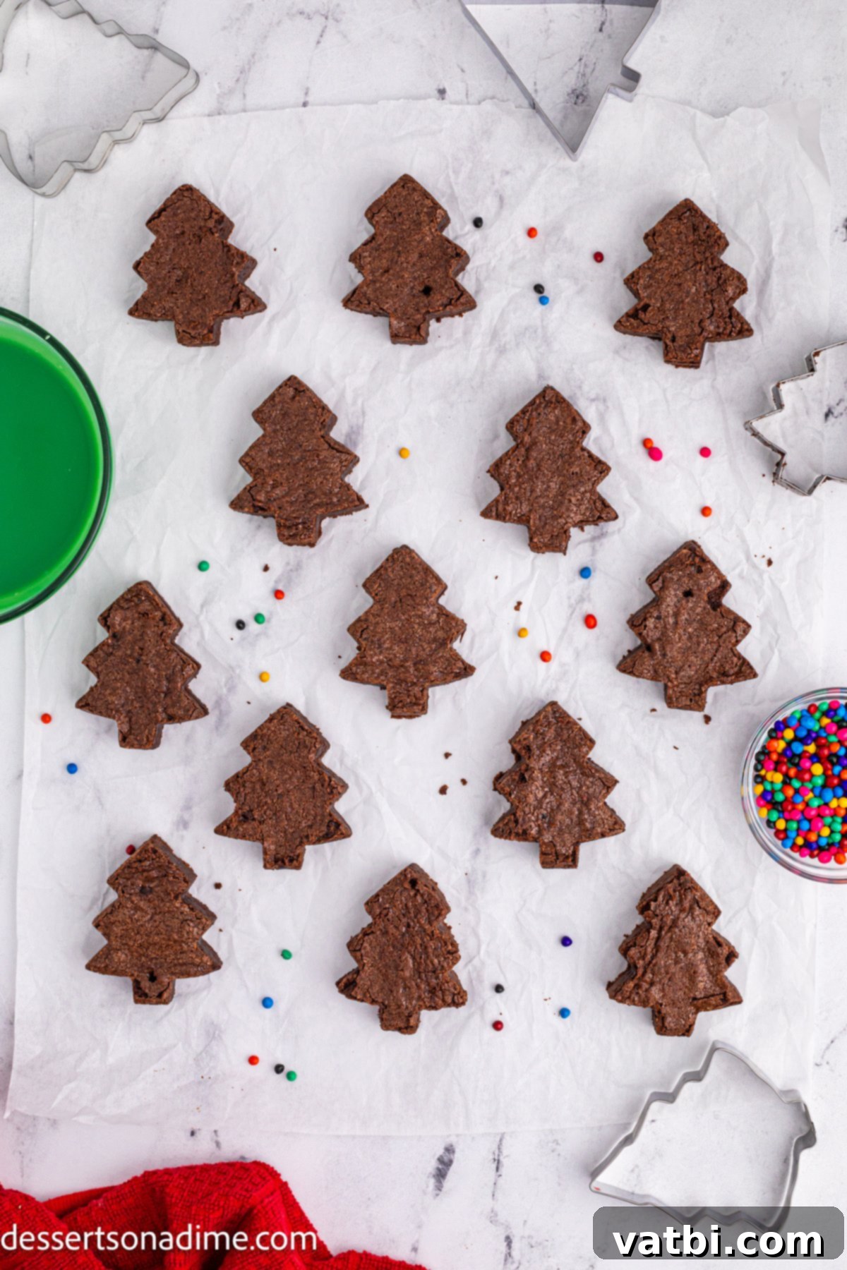 Little Debbie Inspired Christmas Tree Brownies 7 Individual Christmas tree-shaped brownies arranged on a counter, ready for the green topping and decorations.