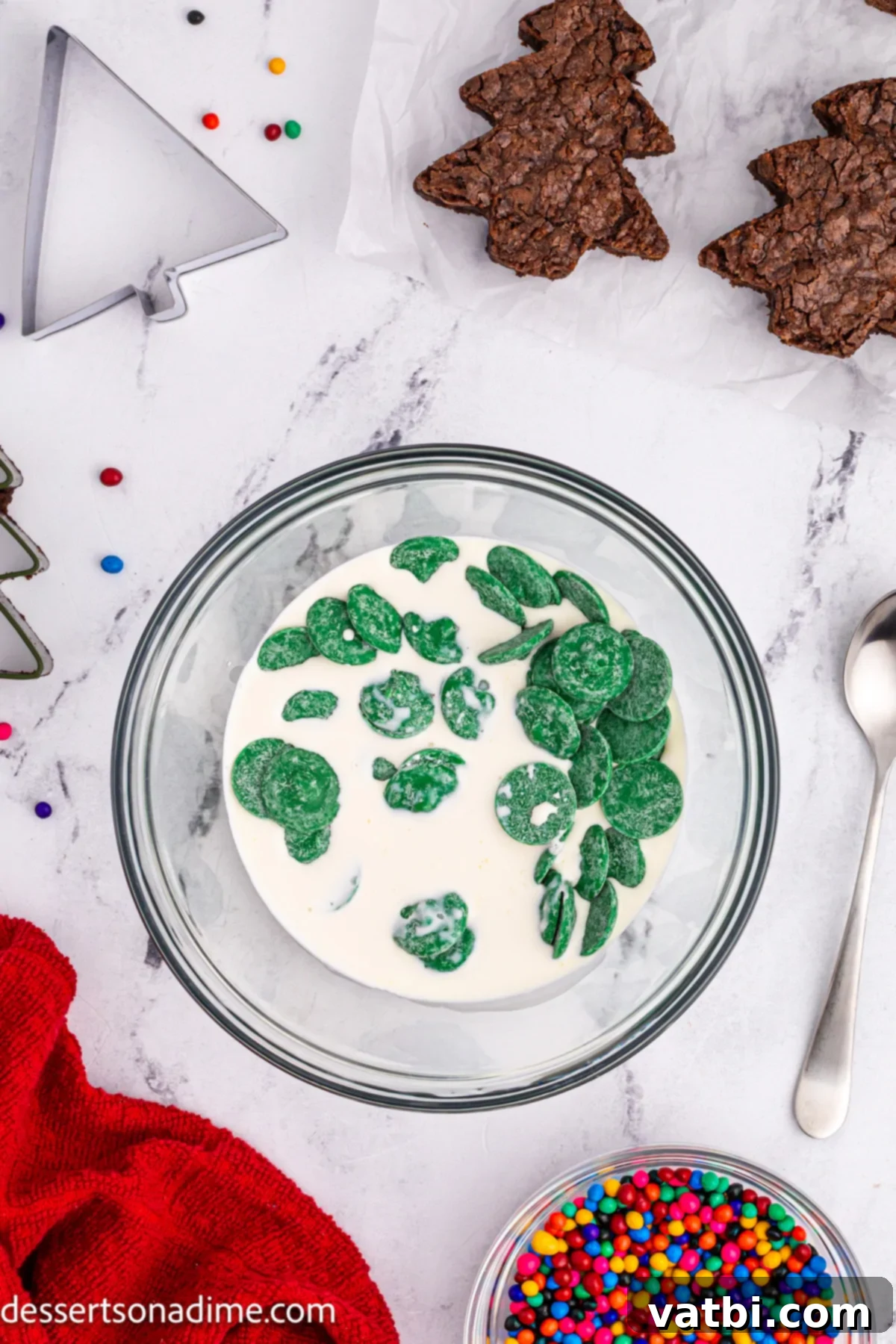 Little Debbie Inspired Christmas Tree Brownies 8 Green candy melts and heavy whipping cream combined in a microwave-safe bowl, ready to be melted for the topping.
