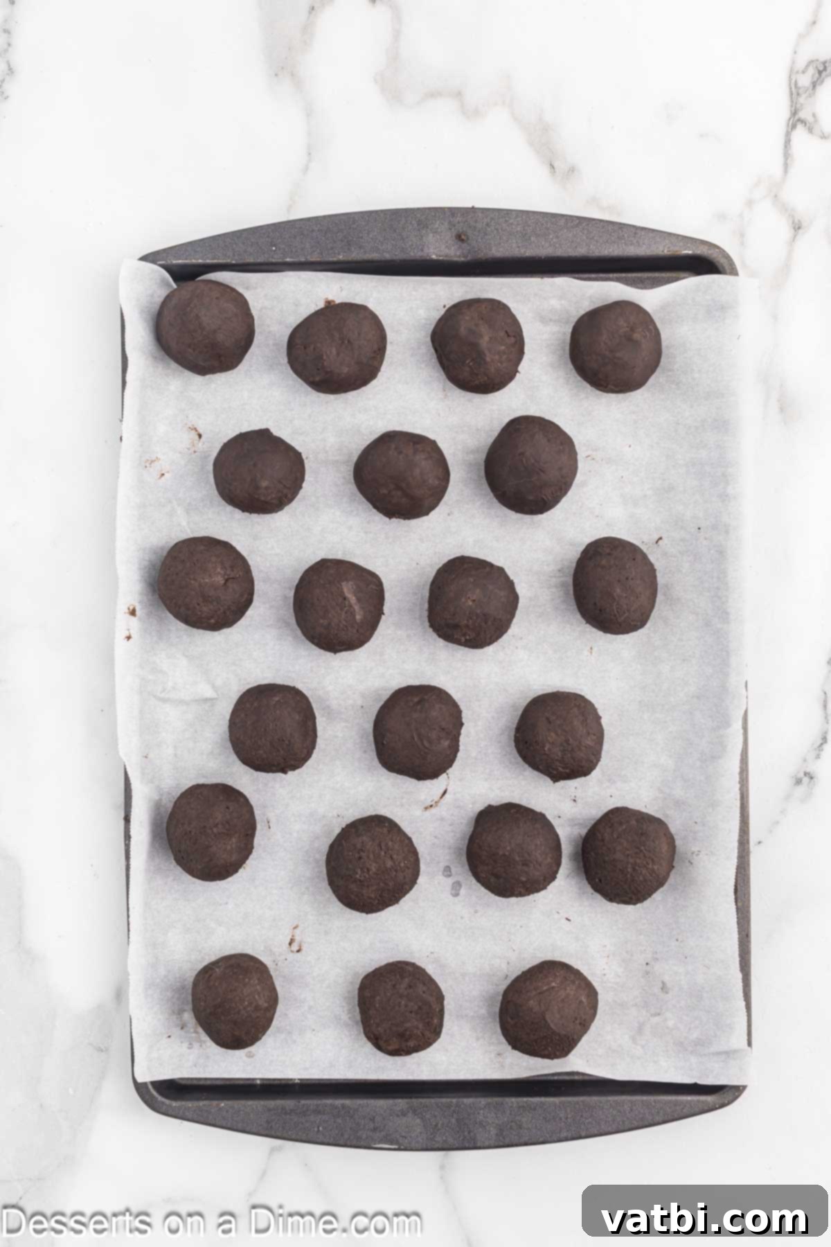 Uniformly shaped Oreo Balls neatly arranged on a baking sheet lined with parchment paper, chilling in the refrigerator.