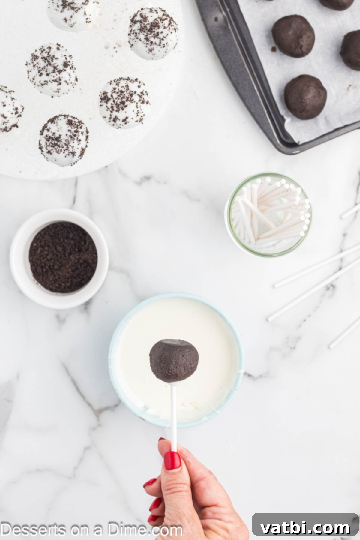 Chilled Oreo Cake Pops with lollipop sticks inserted, ready to be dipped into the smooth, melted white candy coating.