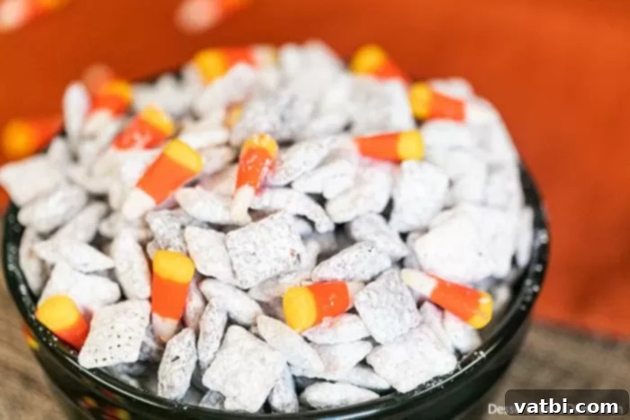 Monster Munch Puppy Chow 5 Halloween Puppy Chow in a serving bowl, garnished with candy corn and candy eyes.