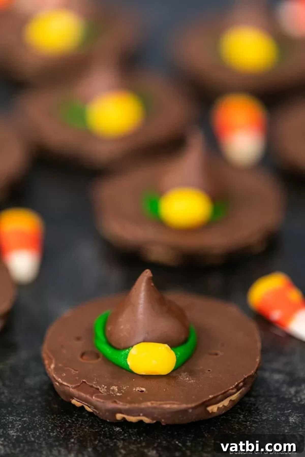Witch hat cookies are the perfect no bake treat and they are easy to make for Halloween with hershey kisses. Halloween witch hat cookies decorated make the cutest treat for parties and more. #dessertonadime #witchhatcookies #harrypotter A cluster of beautifully decorated Witch Hat Cookies, complete with green icing and candy corn buckles, ready for a Halloween party.