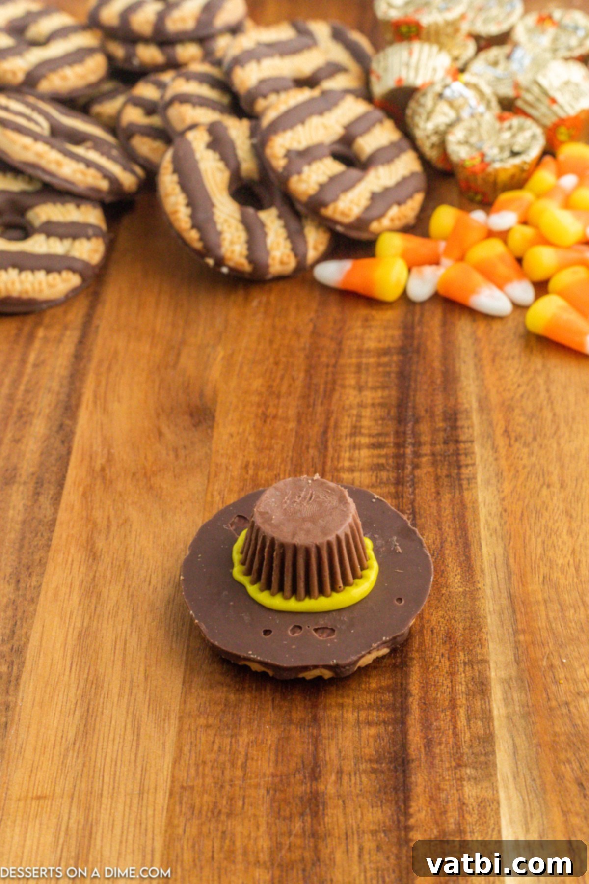 Miniature Reese's Peanut Butter Cup placed upside down onto the yellow icing on the cookie, ready to be pressed.