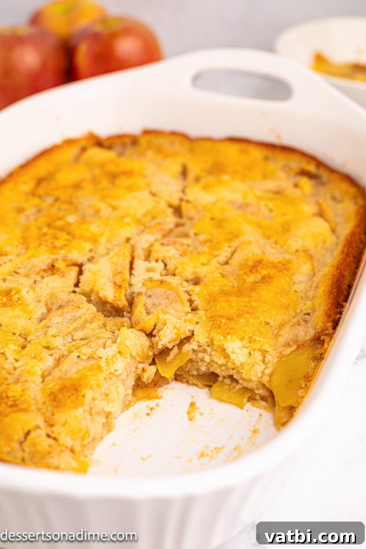 Golden Apple Cobbler Perfection 11 A freshly baked apple cobbler in a large baking dish, featuring a golden, biscuit-like topping and visible bubbly apple filling around the edges.
