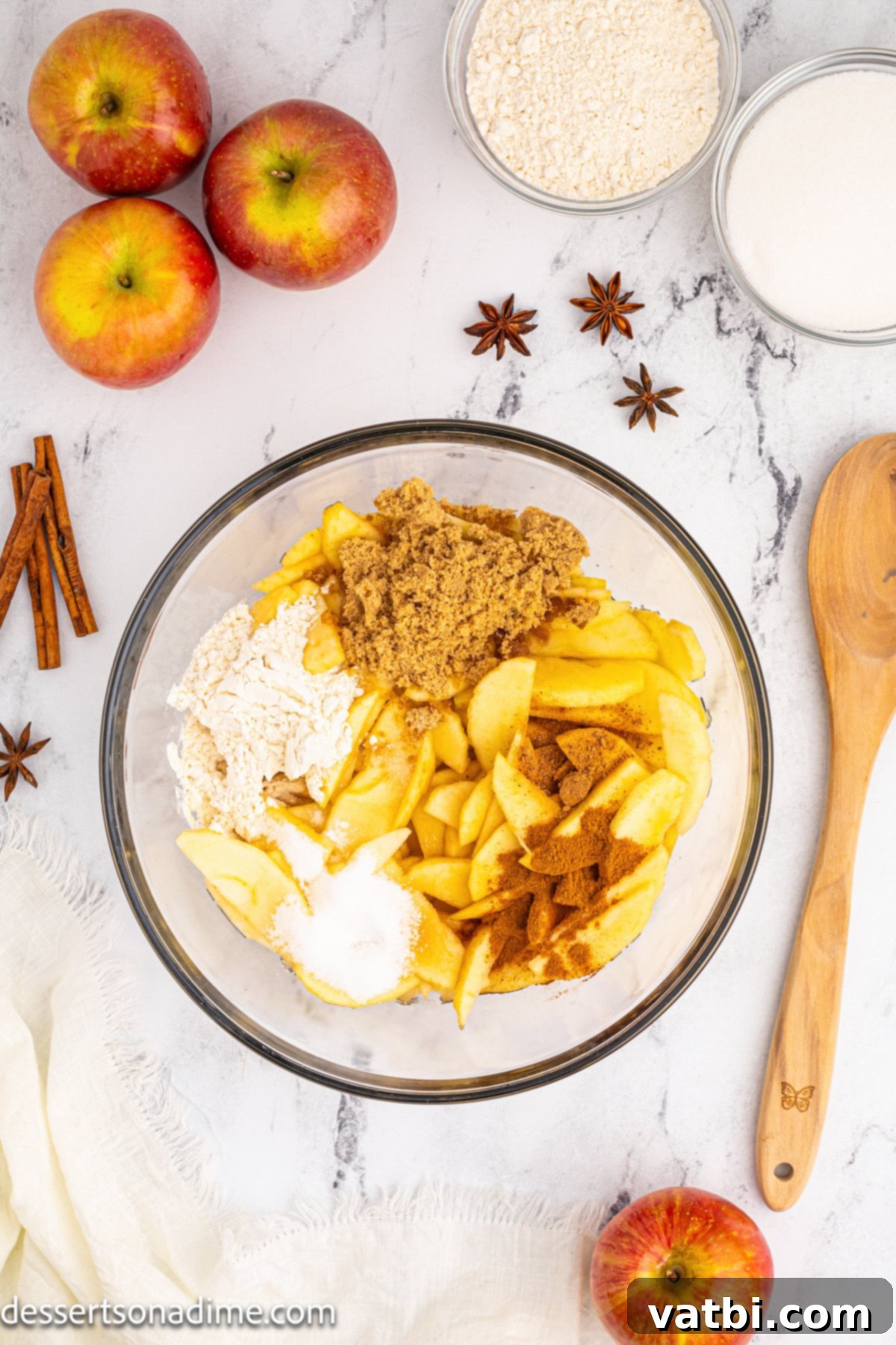 Golden Apple Cobbler Perfection 4 A large bowl filled with sliced apples, brown sugar, granulated sugar, flour, lemon juice, cinnamon, and nutmeg, all thoroughly mixed together for the cobbler filling.