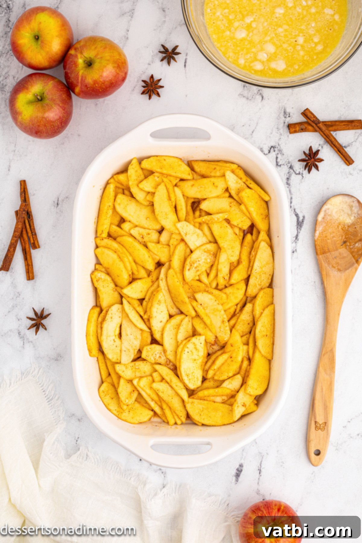Golden Apple Cobbler Perfection 5 The apple mixture, perfectly coated in spices and sugars, evenly spread in a 9x13 baking dish, ready for the topping.