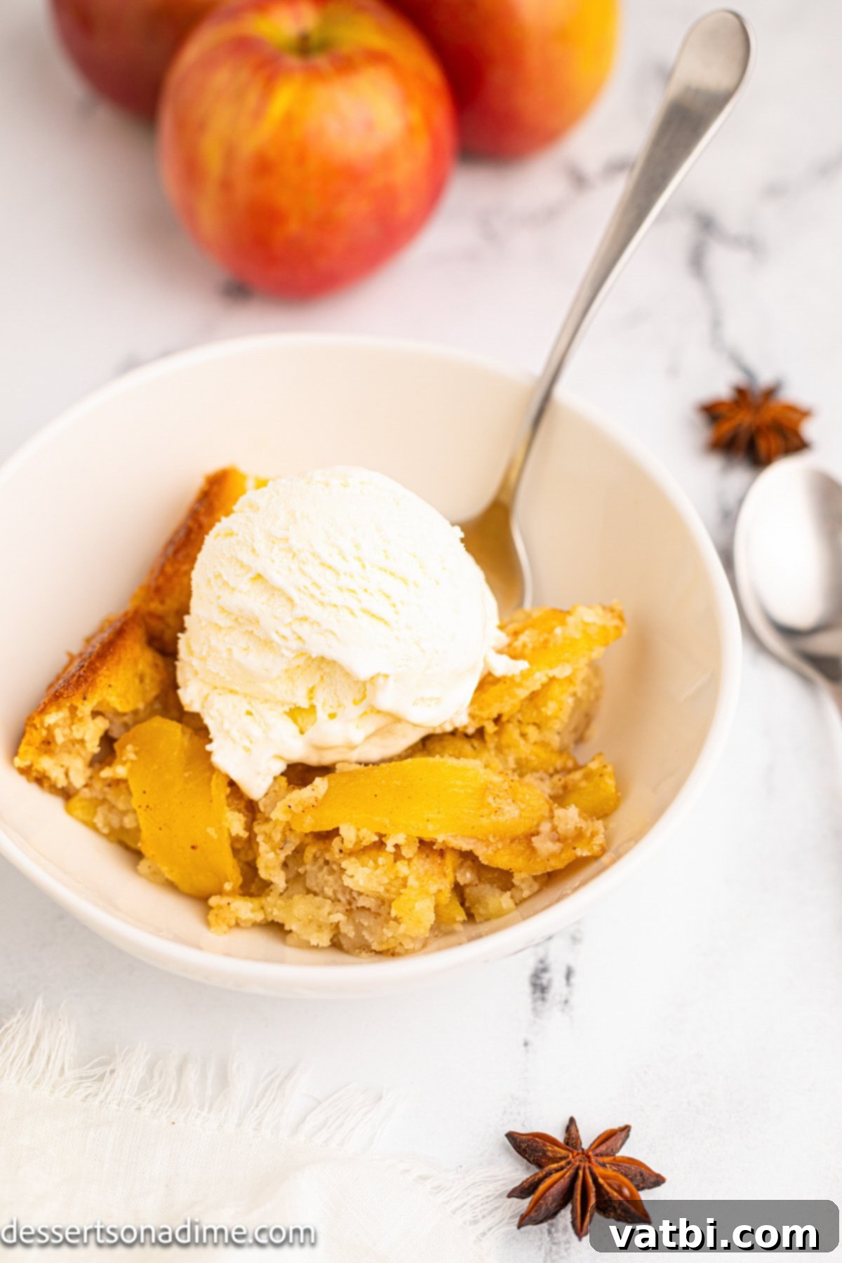 Golden Apple Cobbler Perfection 10 Two bowls of warm apple cobbler, generously topped with melting vanilla ice cream, on a wooden table.