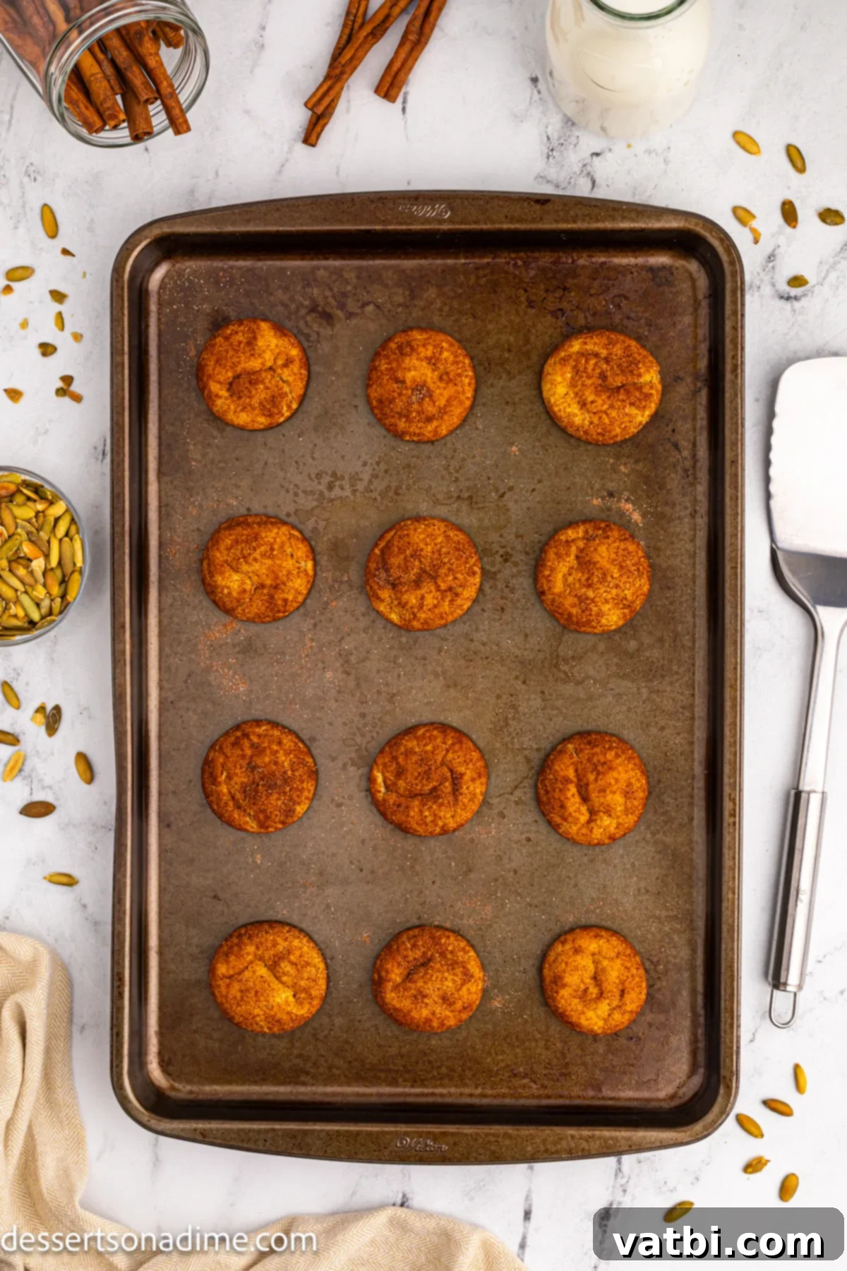 Autumn Spice Pumpkin Snickerdoodles 11 Freshly baked cookies cooling on the baking sheet before being transferred to a wire rack.