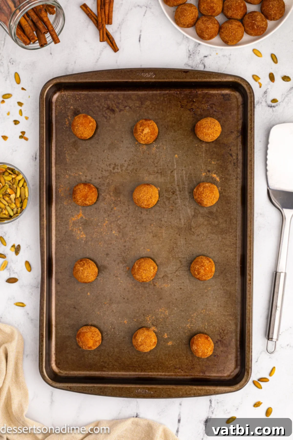 Autumn Spice Pumpkin Snickerdoodles 10 Dough balls spaced out on a baking sheet lined with parchment paper.