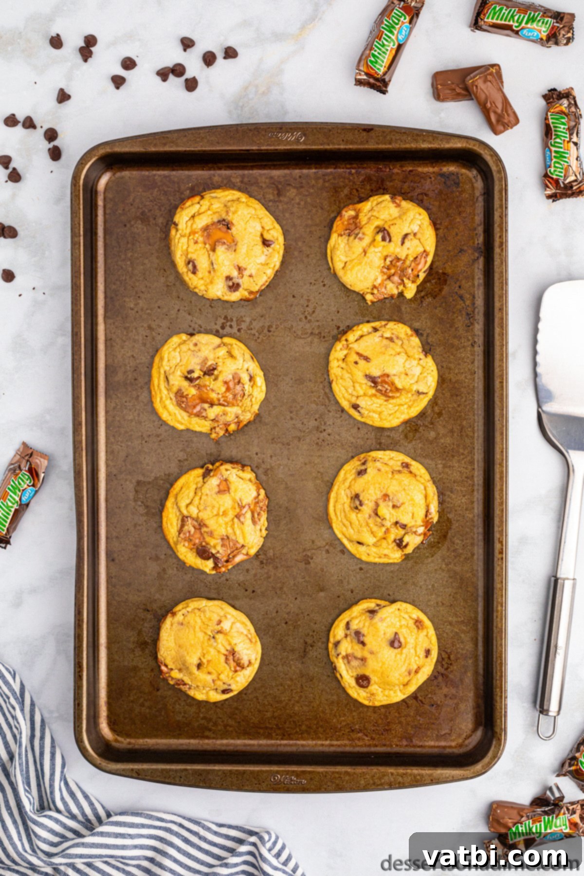 Freshly baked Milky Way cookies cooling on a baking sheet.