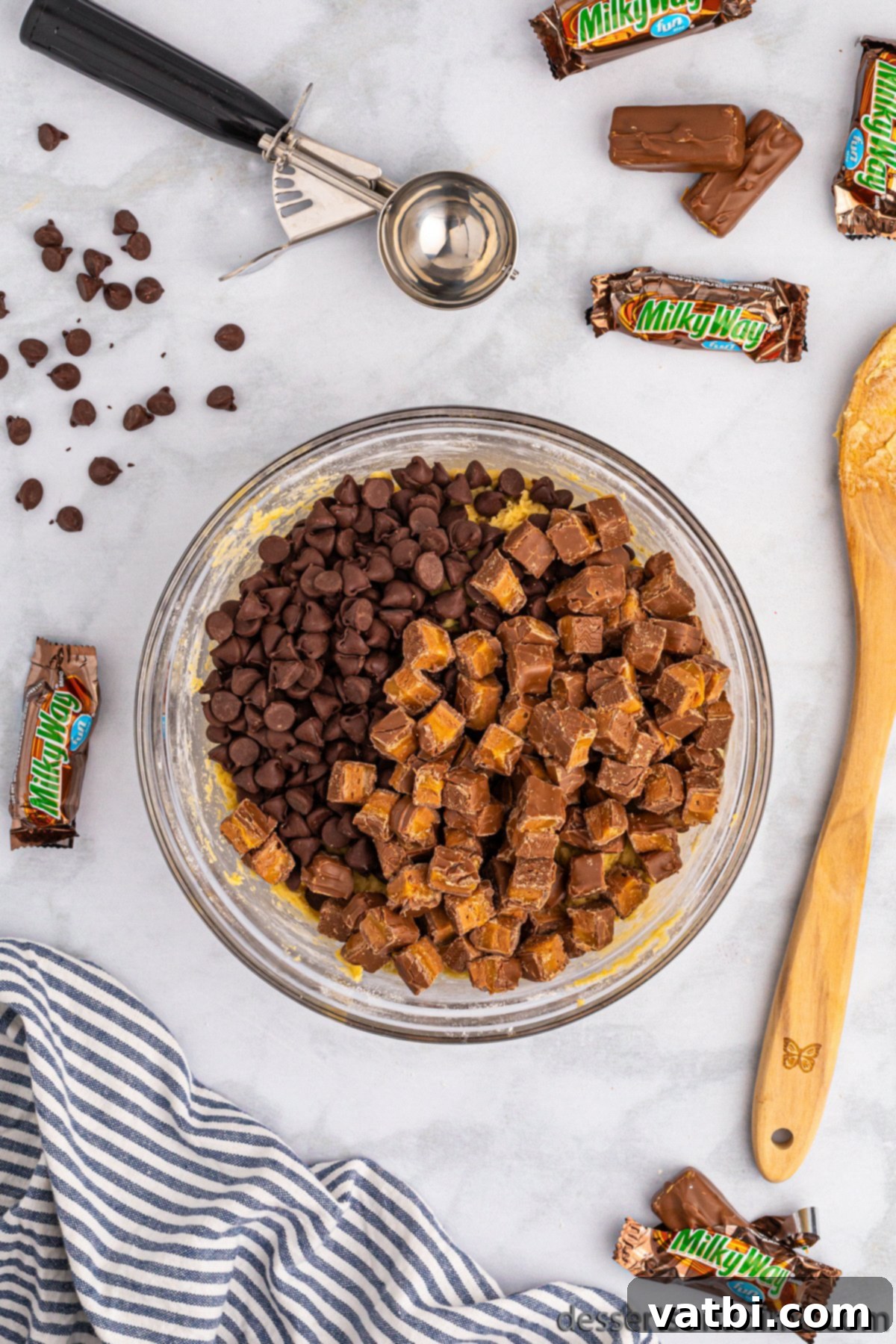 Chopped Milky Way candy bars and chocolate chips being folded into the cookie dough.