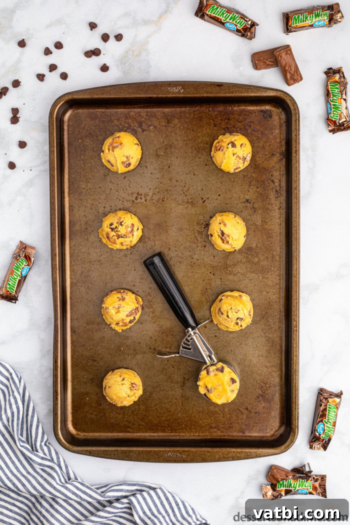 Scooped cookie dough balls placed on a baking sheet lined with parchment paper.