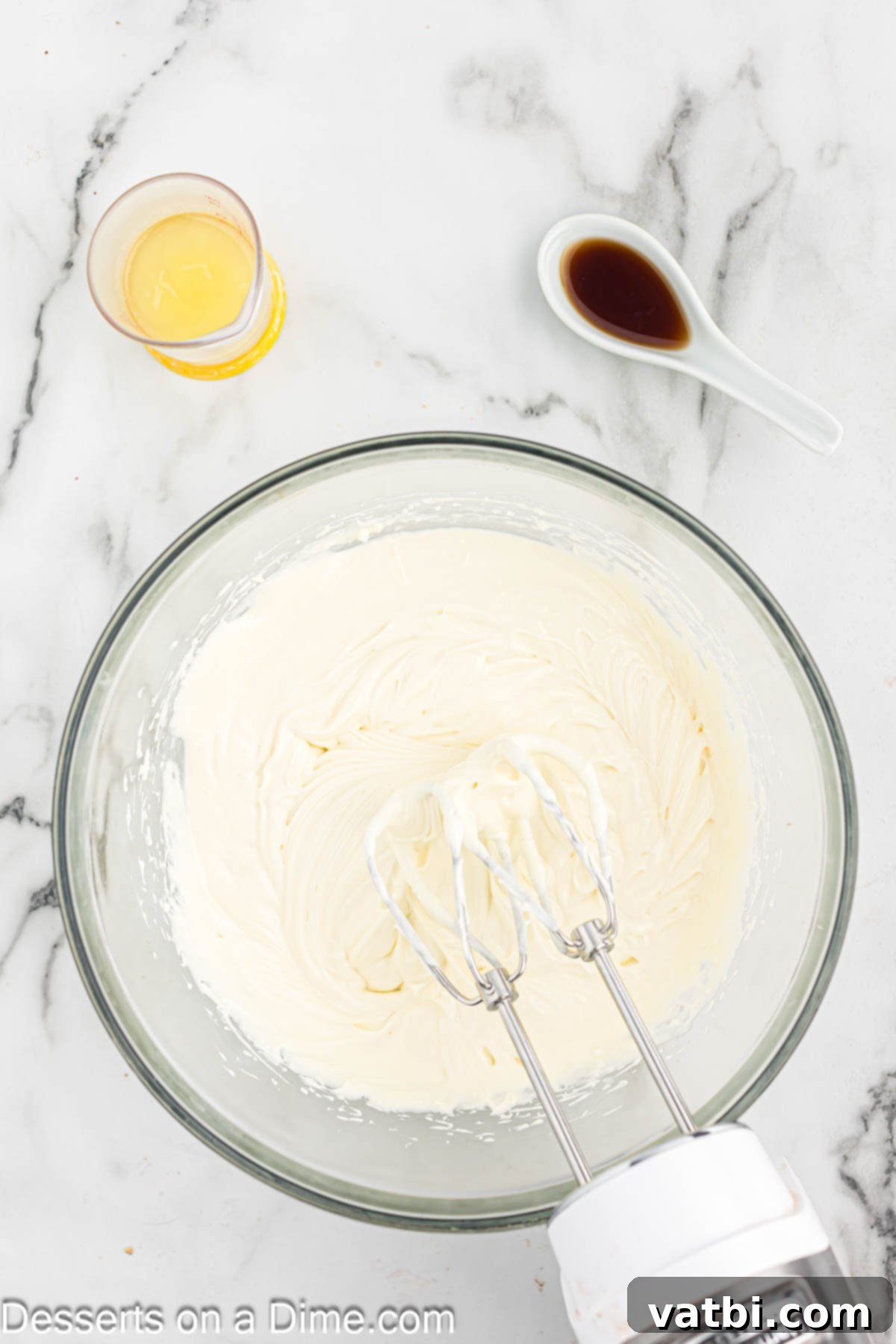 Effortless No-Bake Cheesecake 7 Mixing bowl with cream cheese, sweetened condensed milk, lemon juice, and vanilla extract being combined.