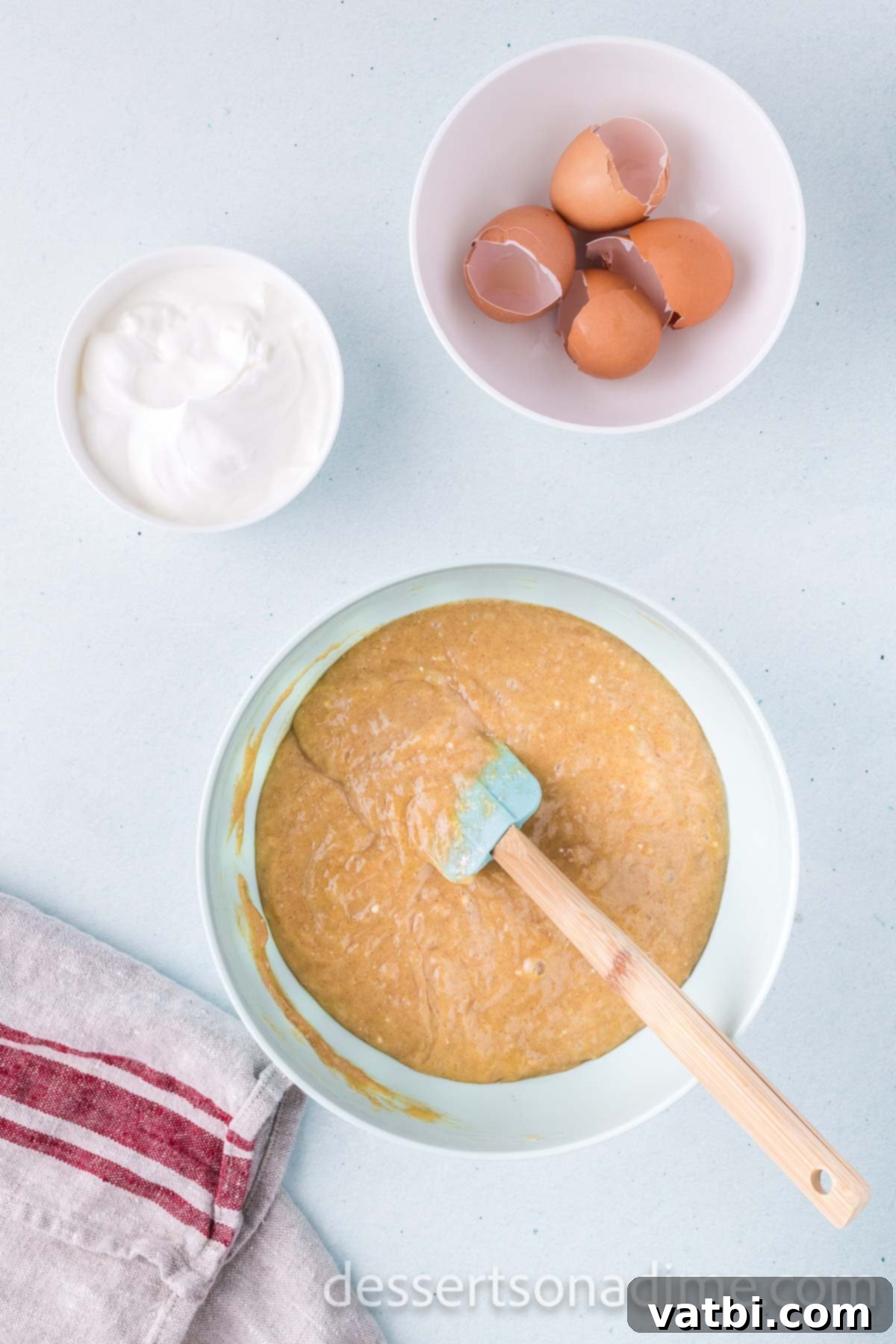 Gently stirring sour cream into the prepared cake mix batter in a mixing bowl.