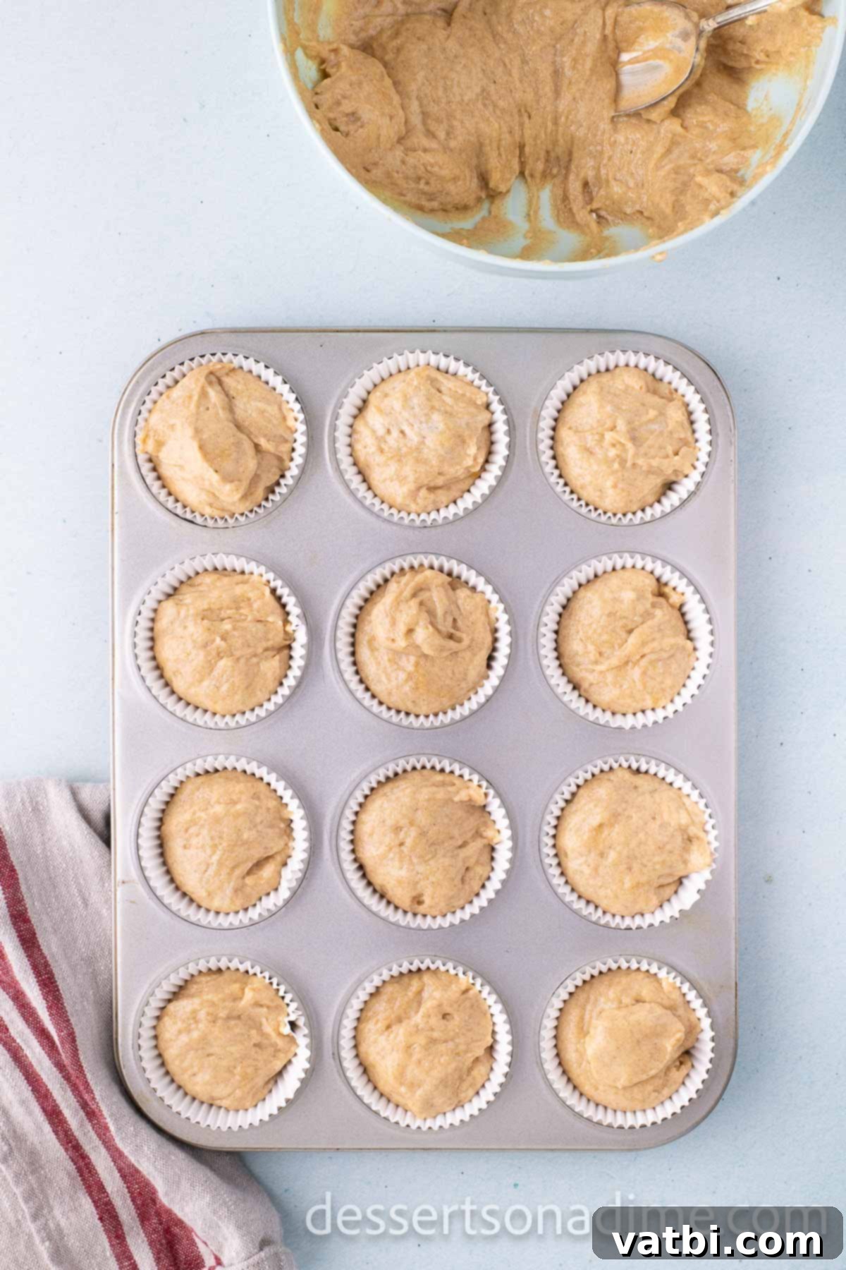 Pouring the cupcake batter into lined muffin tins, filling each liner approximately three-quarters full.
