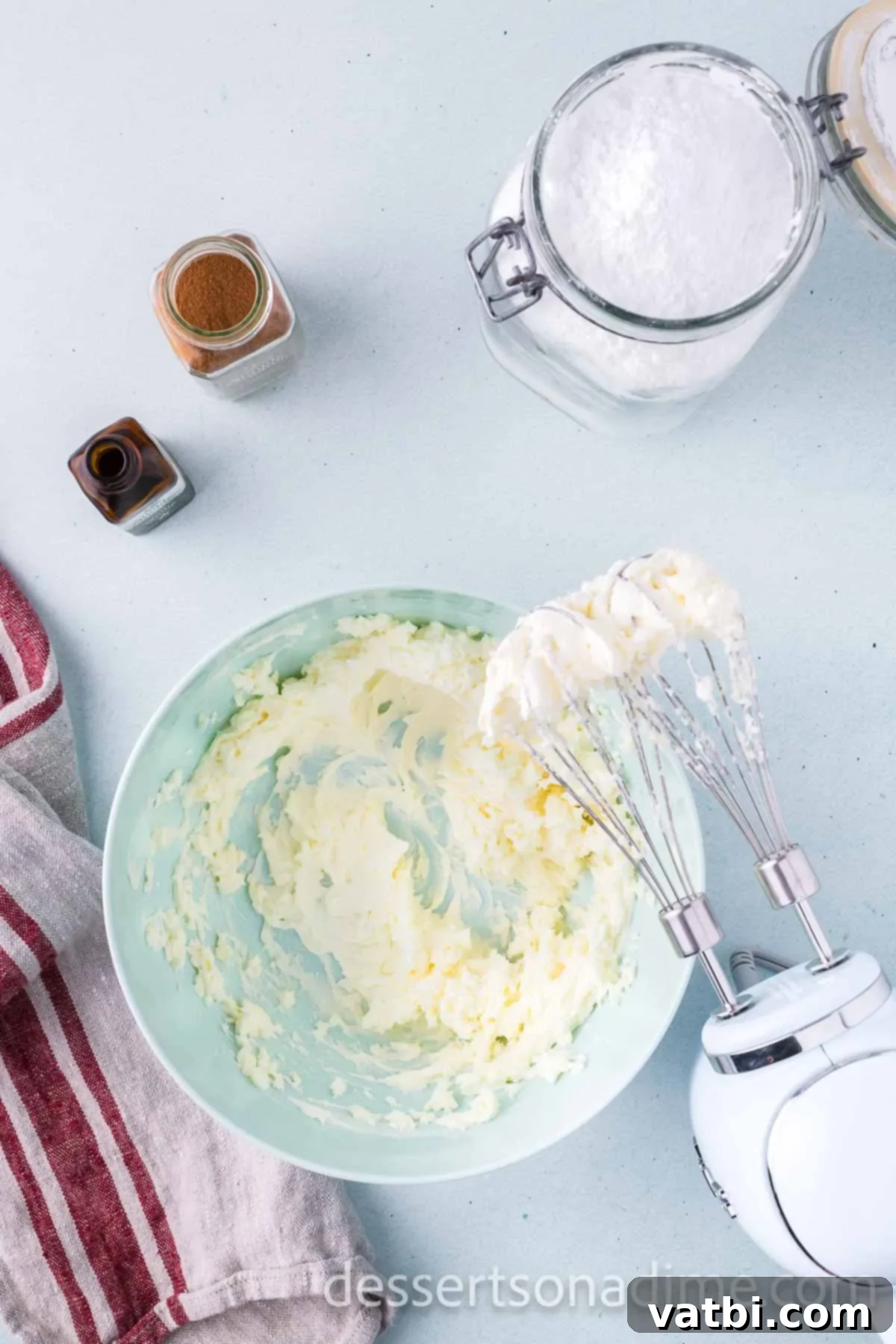 Beating together softened cream cheese and unsalted butter in a medium bowl using a handheld electric mixer.