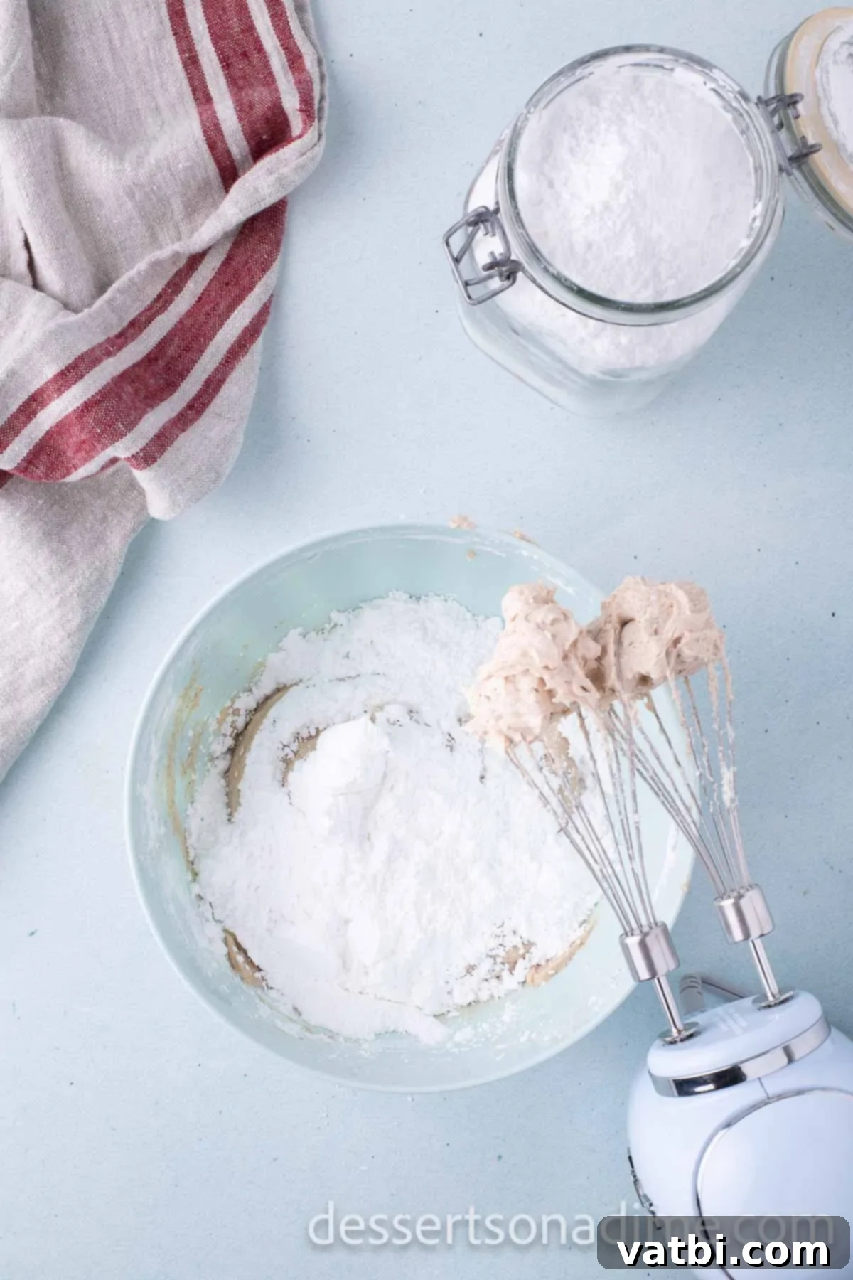 Gradually adding powdered sugar to the cream cheese and butter mixture in a bowl, mixing until combined.