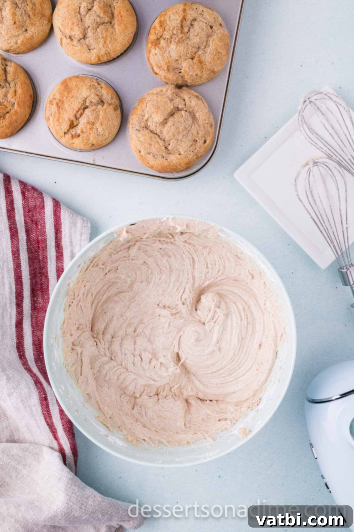 Stirring in vanilla extract and ground cinnamon into the smooth cream cheese frosting in a bowl.