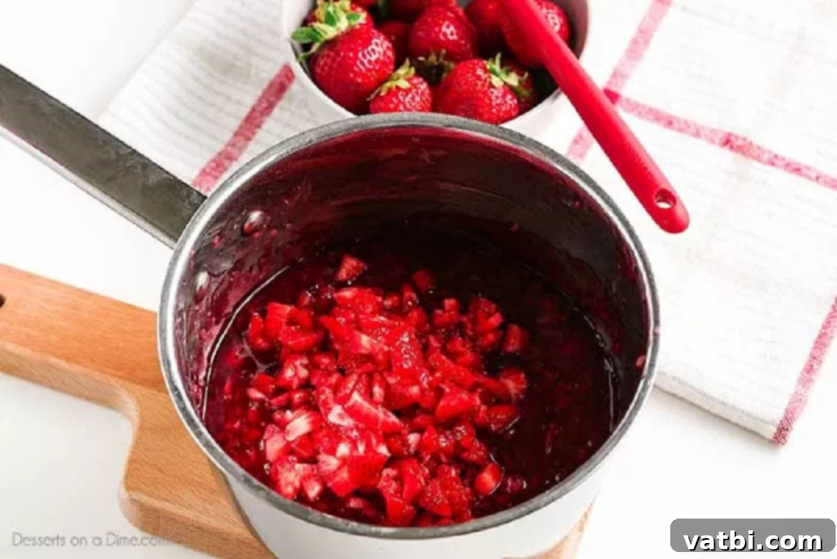 Sweet Strawberry Sauce Recipe 4 Diced fresh strawberries being stirred into a simmering red sauce in a saucepan.